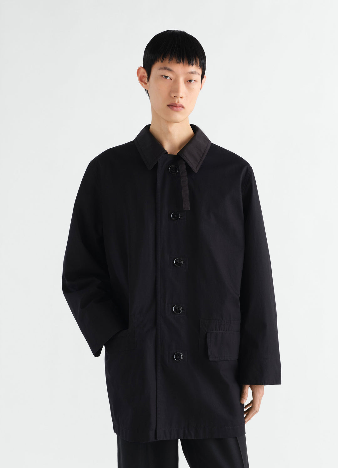 Raincoat in black water-repellent Ventile® cotton twill by LEMAIRE worn by a model front view