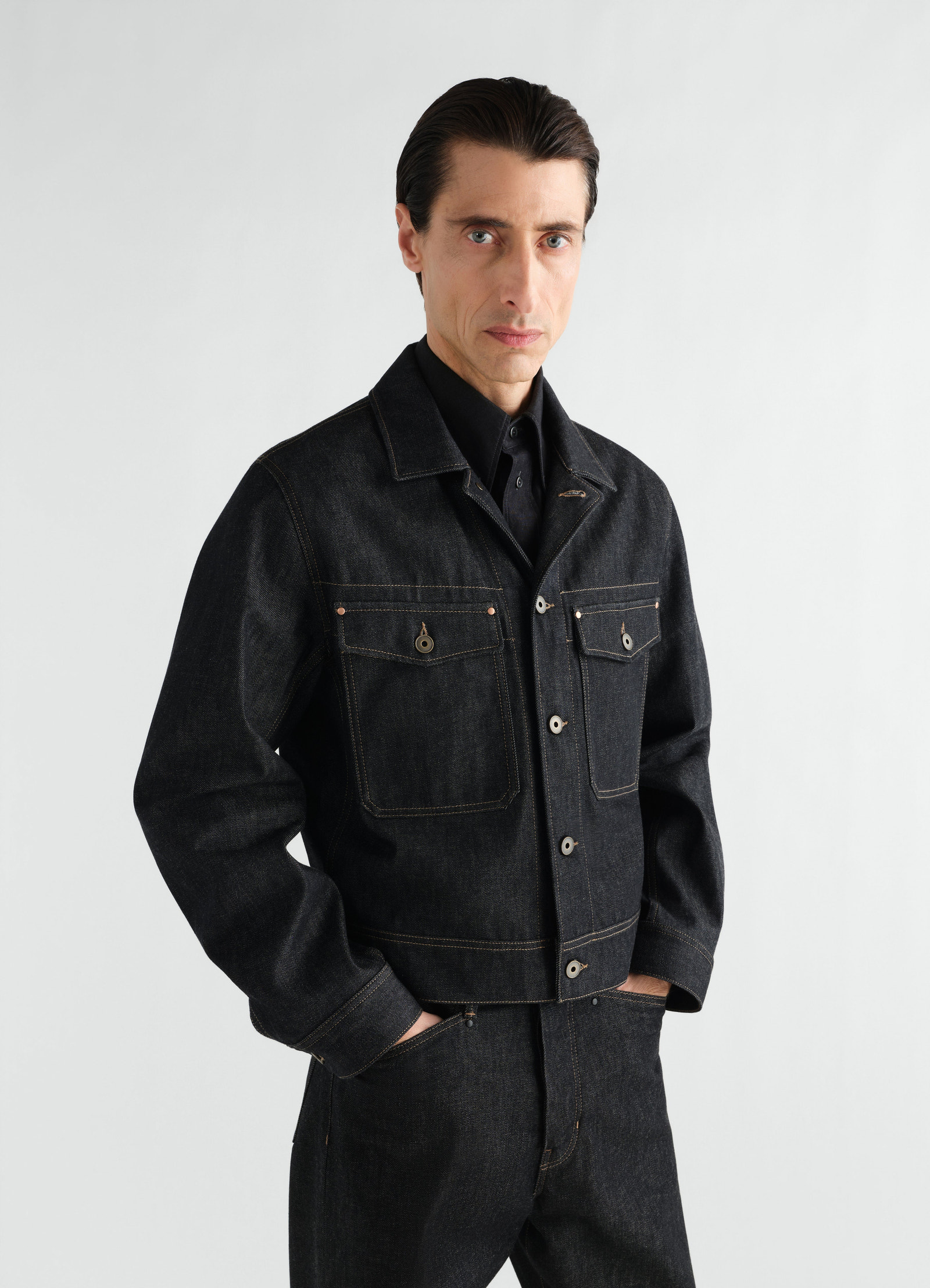 Trucker jacket in slate denim with button pockets worn by model front view lemaire