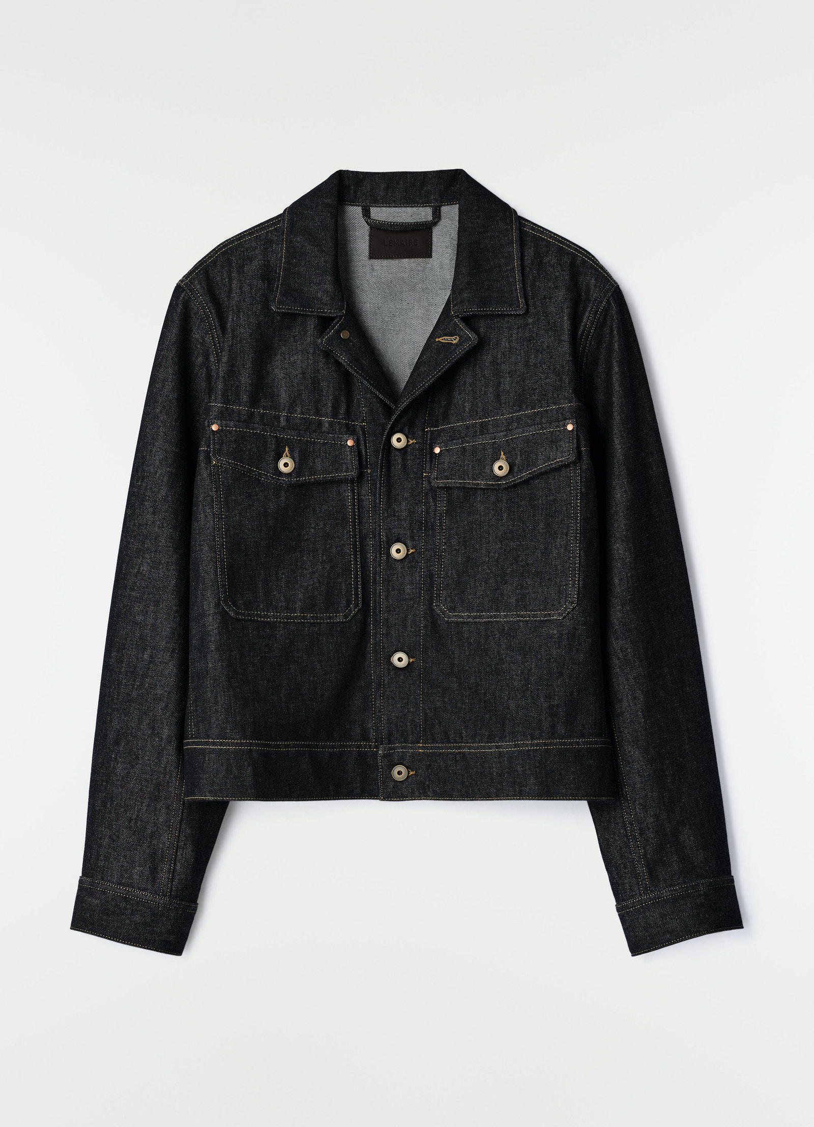 Trucker jacket in dark indigo denim with beige buttons and contrast stitching by lemaire on white background
