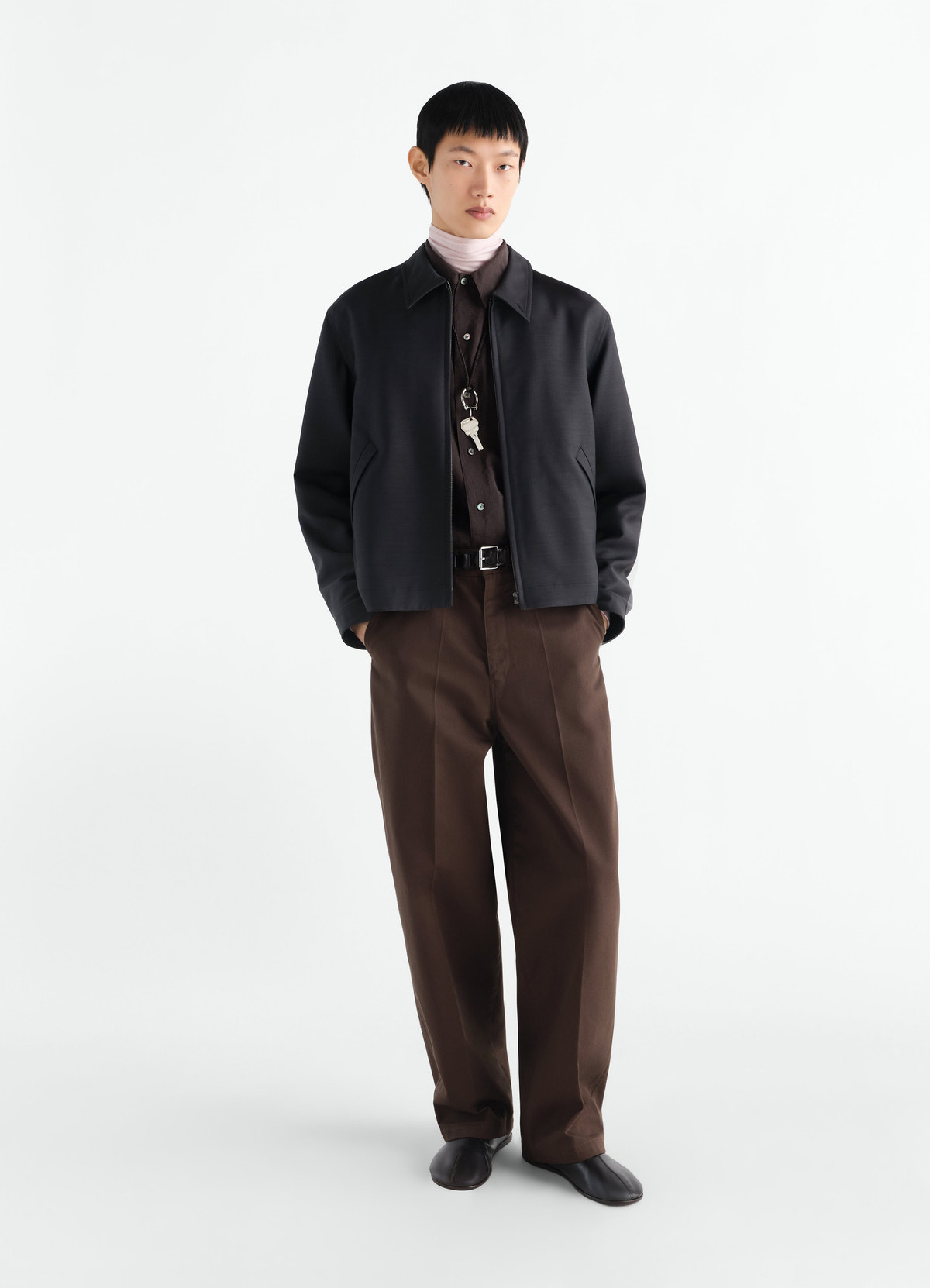 Zipped black wool and viscose blouson worn by model styled with brown pants and light turtleneck lemaire