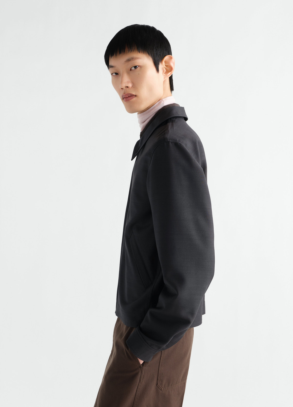 Zipped black wool and viscose blouson by lemaire worn by model side view with brown trousers and pink turtleneck