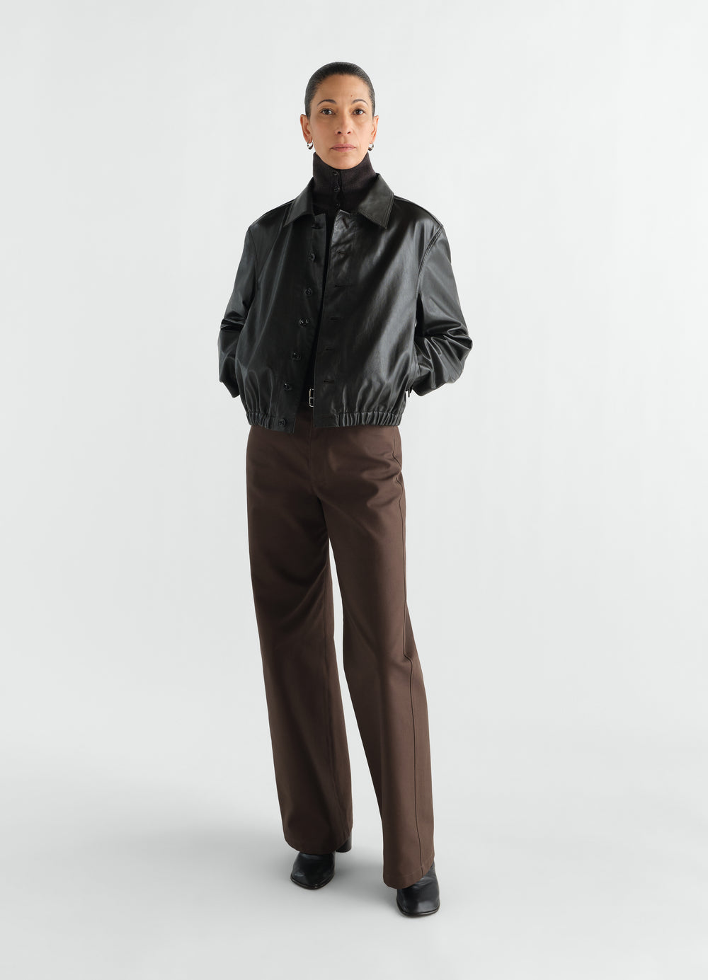 Soft black leather blouson with button front worn by a model in LEMAIRE styled look on white background