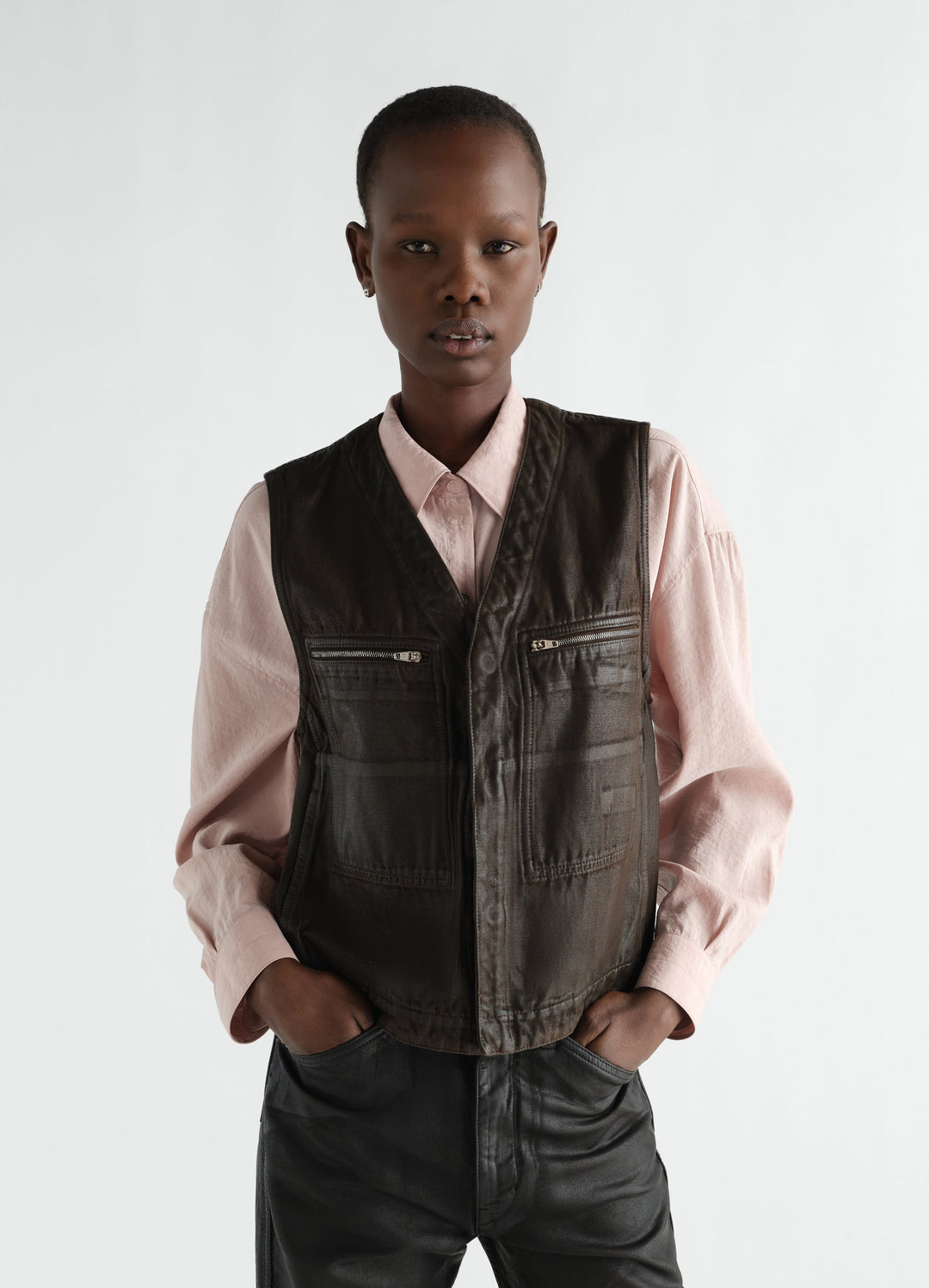 Utility vest LEMAIRE in dark brown coated twill worn by model with pink shirt front view