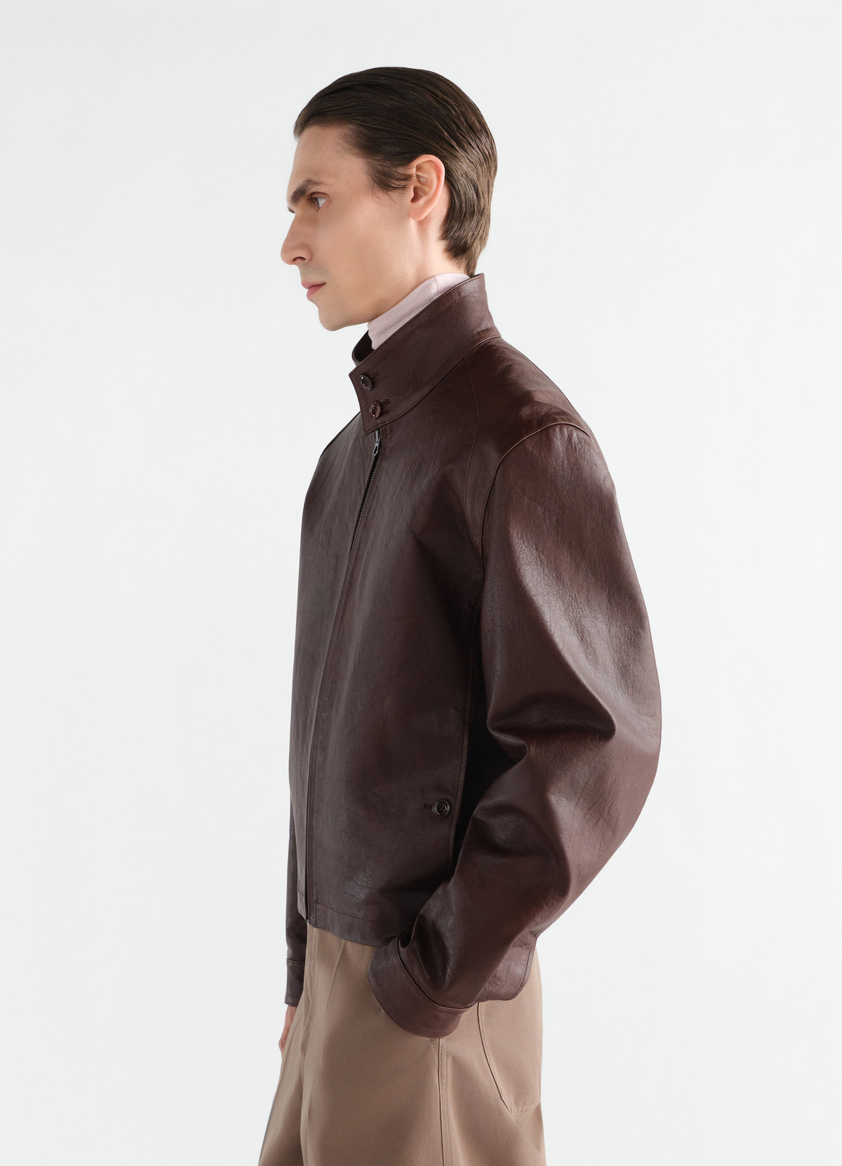Harrington-blouson aus glänzendem rindsleder, in dunkelbraun, von einem model getragen, seitenansicht