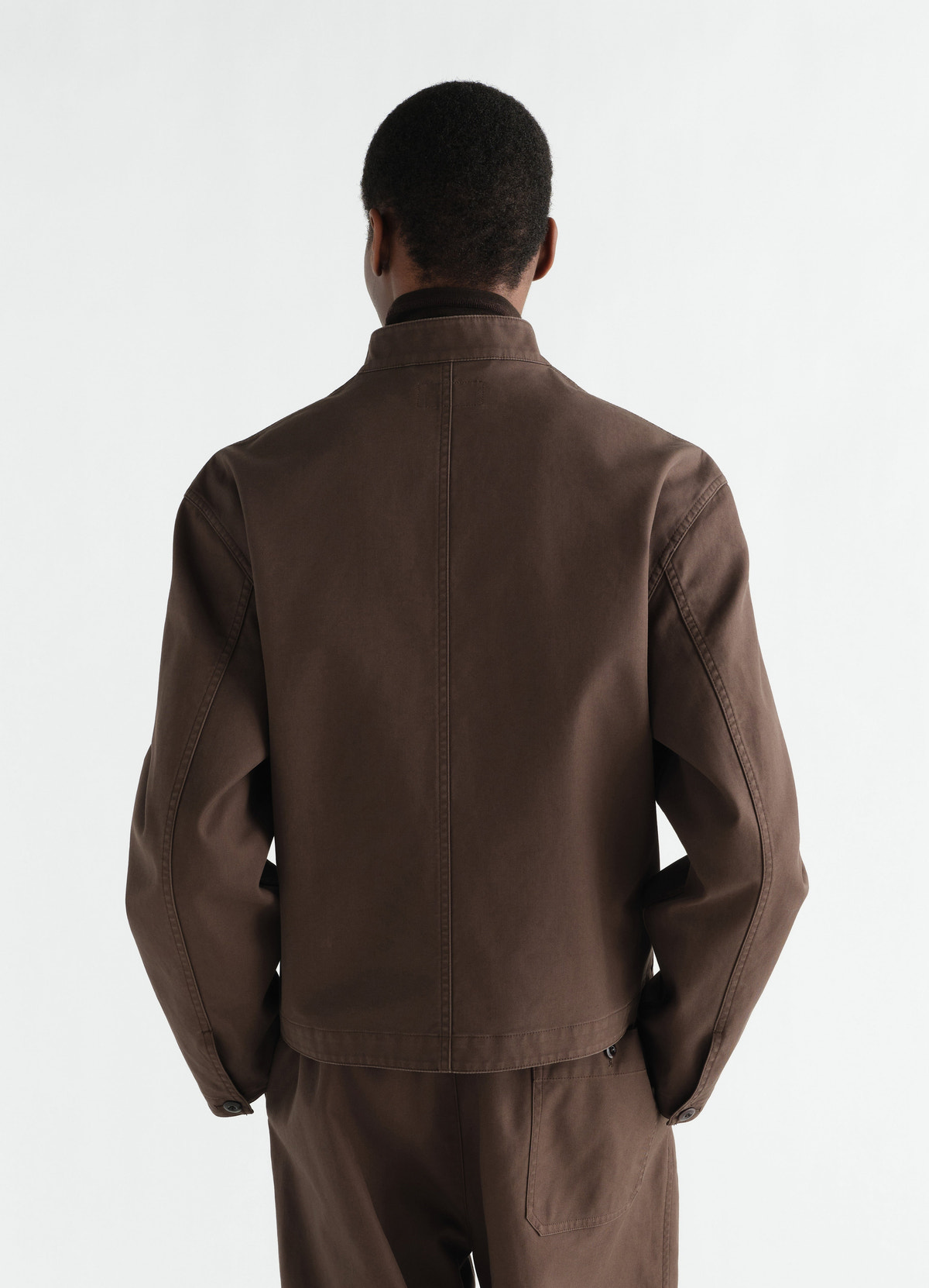 Stand-collar brown heavy cotton twill jacket by lemaire worn by a model shown from back side