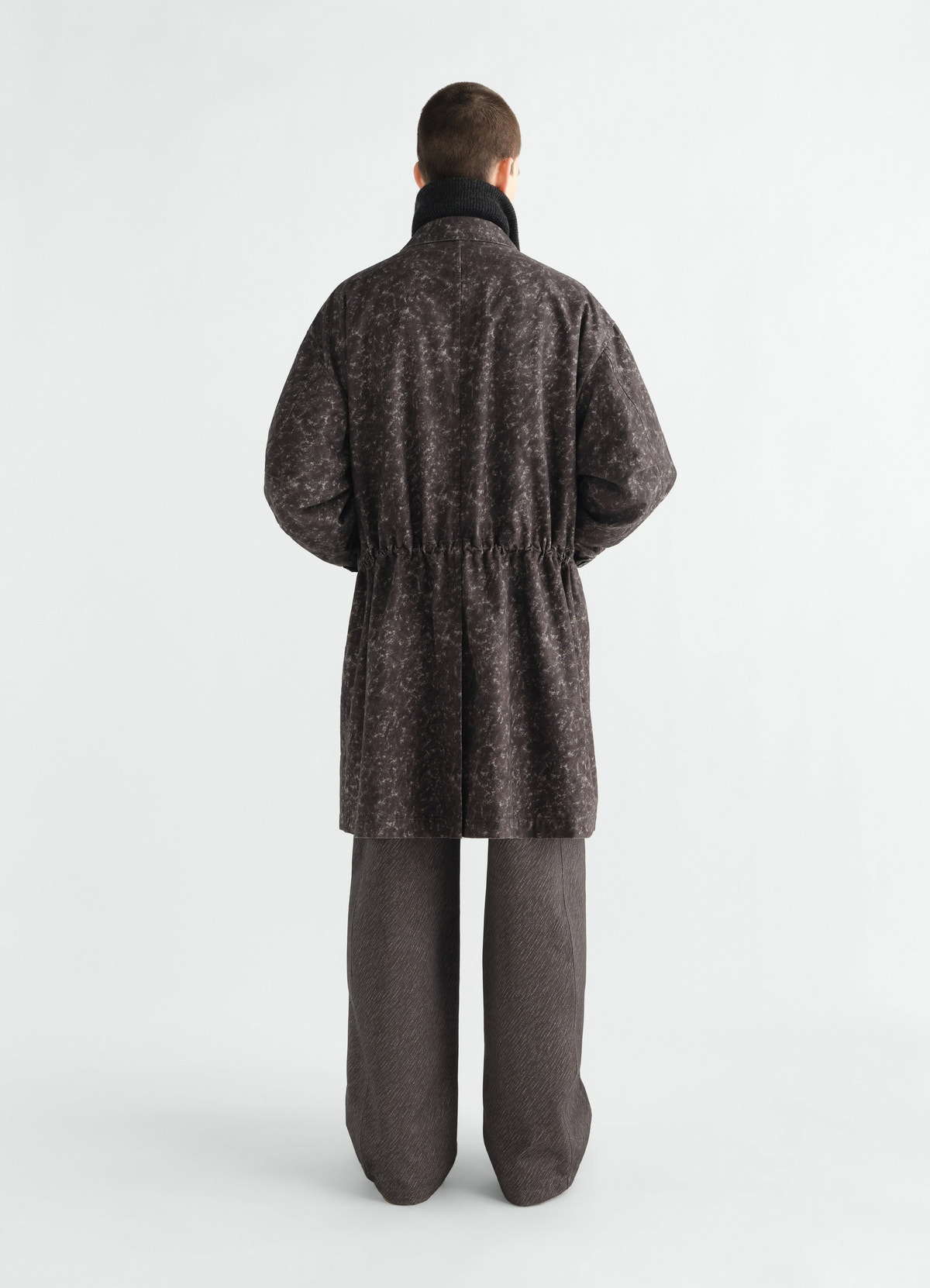 Military parka in grey printed cotton by lemaire worn by model back view with high collar and cinched waist
