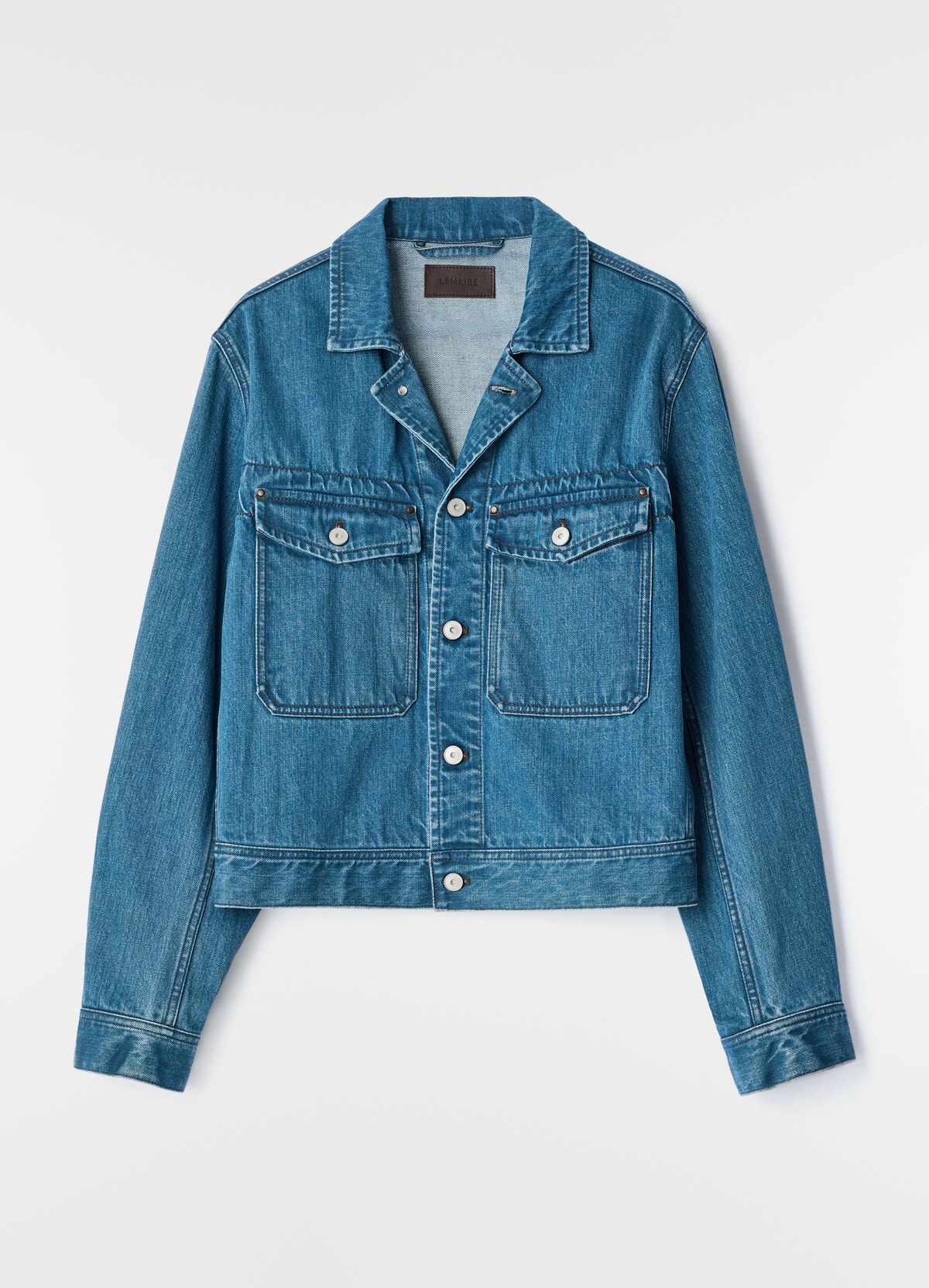 Trucker jacket in indigo selvedge denim with front pockets by lemaire flat lay on white background