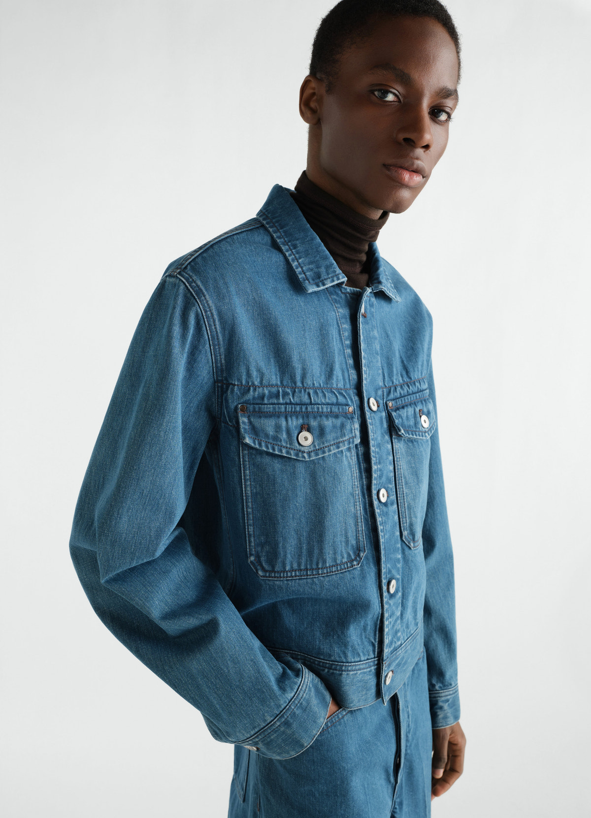 Trucker jacket in indigo selvedge denim by lemaire worn by model side view with front pockets and buttons