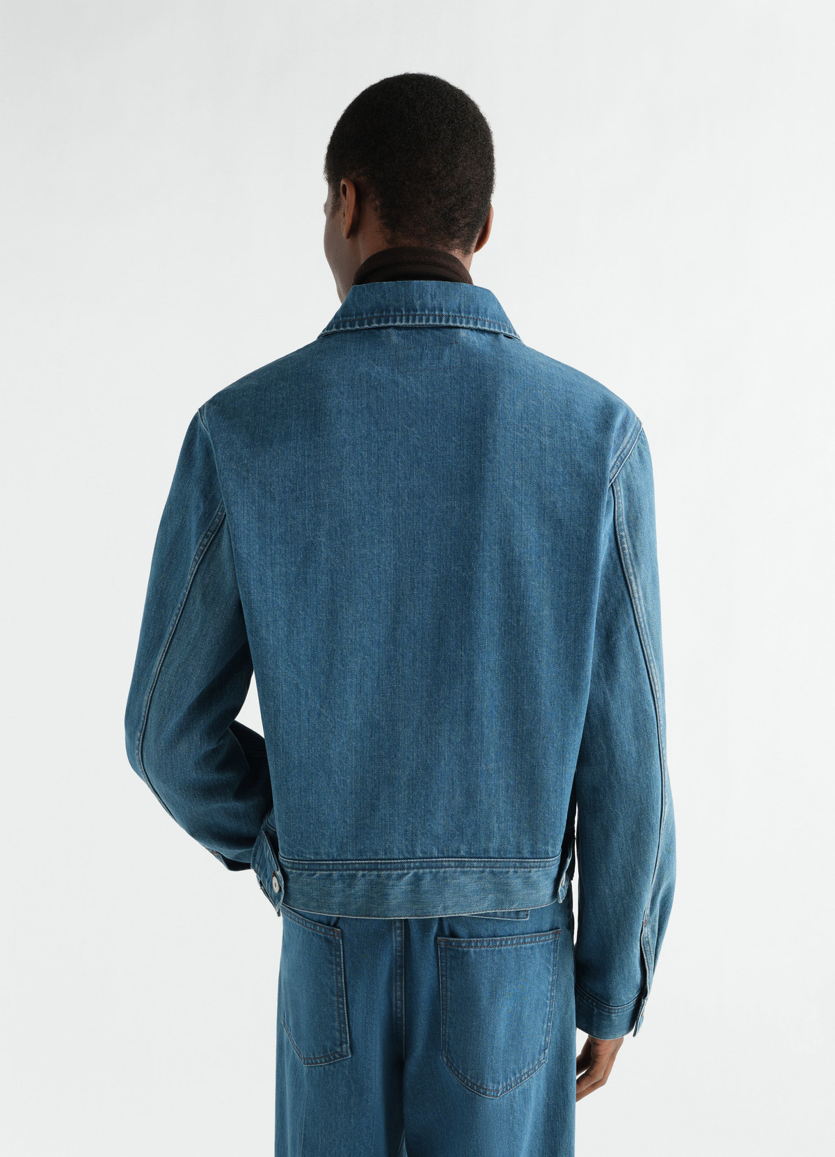 Trucker jacket in indigo selvedge denim by lemaire worn by model back view with matching denim trousers
