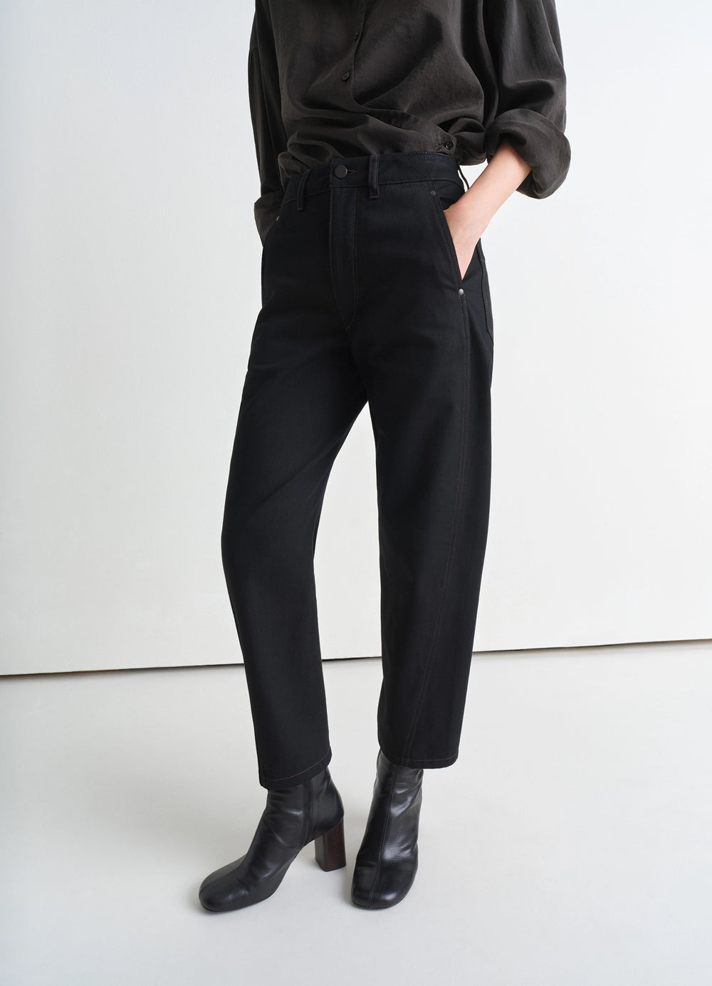 Lemaire Twisted Pants in Deep Black Heavy Denim, model shot, angled side view high waist with subtle taper
