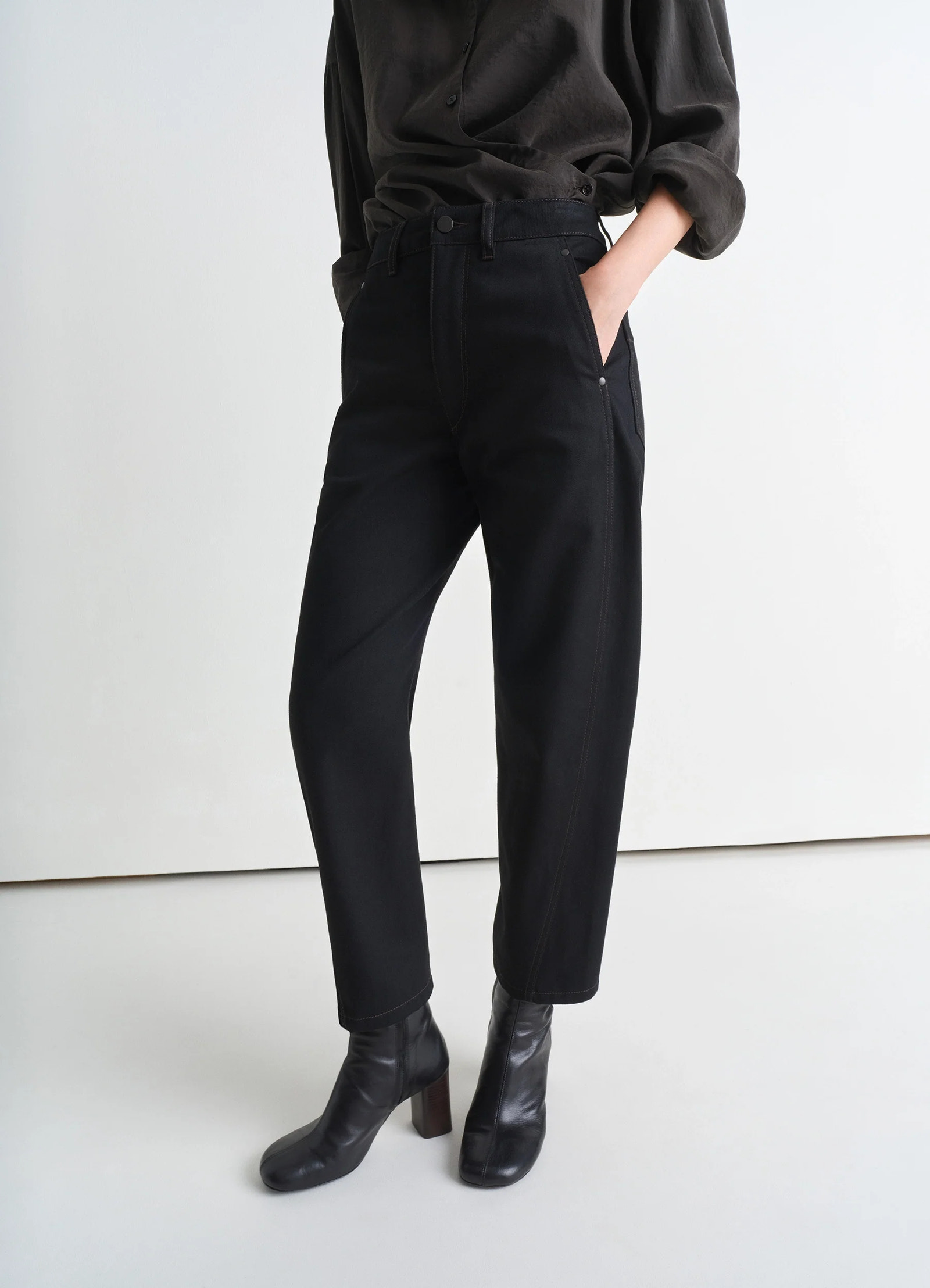 Lemaire twisted pants in deep black heavy denim, model shot, three-quarter view tapered leg