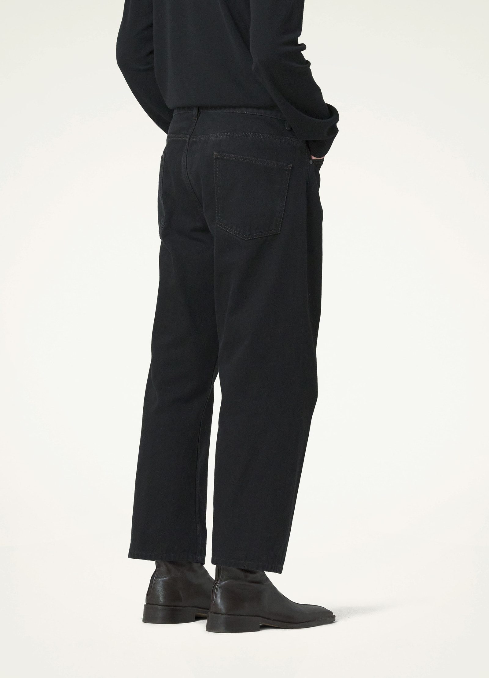 Lemaire curved 5 pocket pants in deep black heavy denim, model shot, back view tapered ankle cut