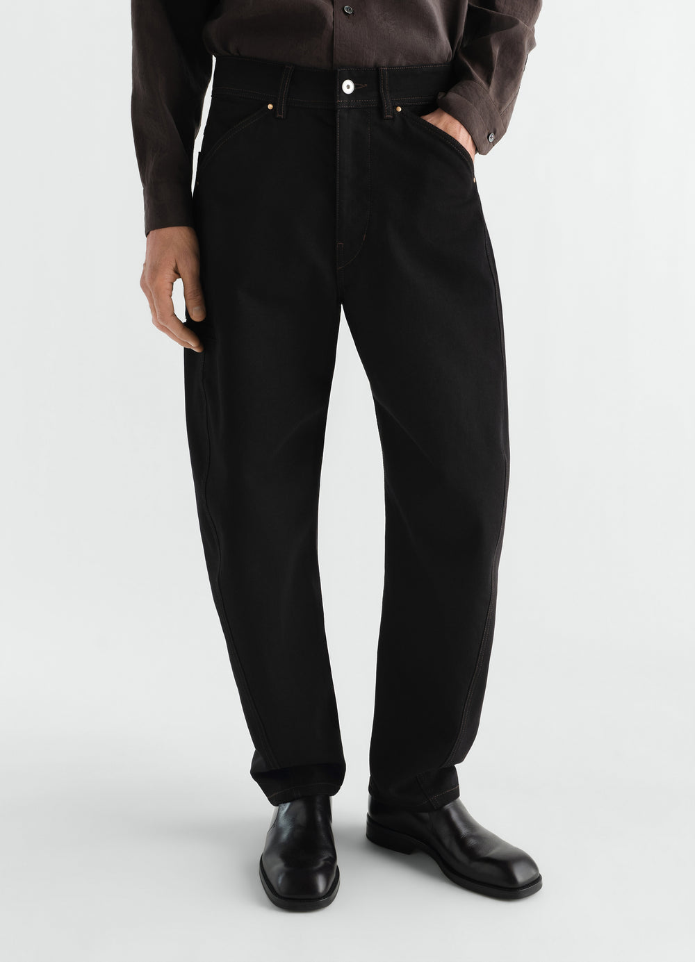 Twisted Workwear Pants LEMAIRE black denim with front pockets worn by a model standing on white background