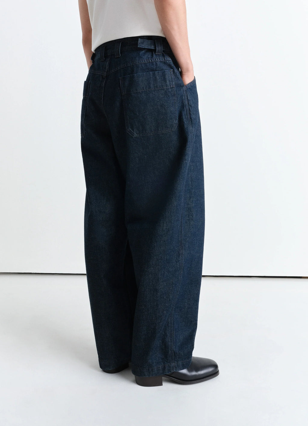 Lemaire Pleated Workwear Pants in Deep Indigo Heavy Denim, model shot, three-quarter rear view loose fit with deep hem