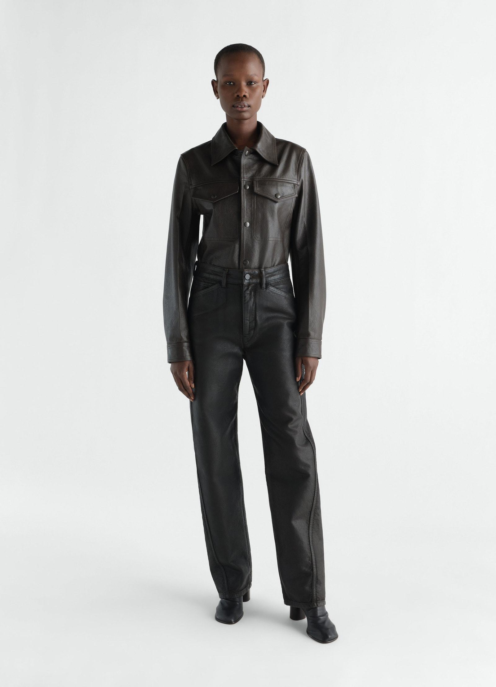 Twisted black coated denim pants worn by model front view lemaire