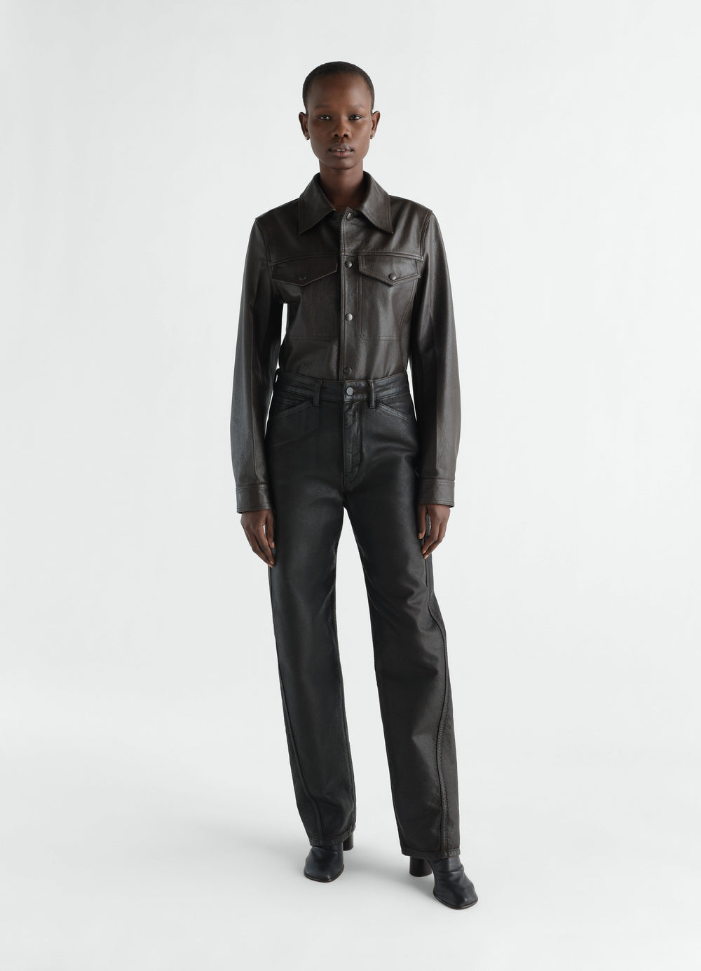 Twisted black coated denim pants worn by model front view LEMAIRE