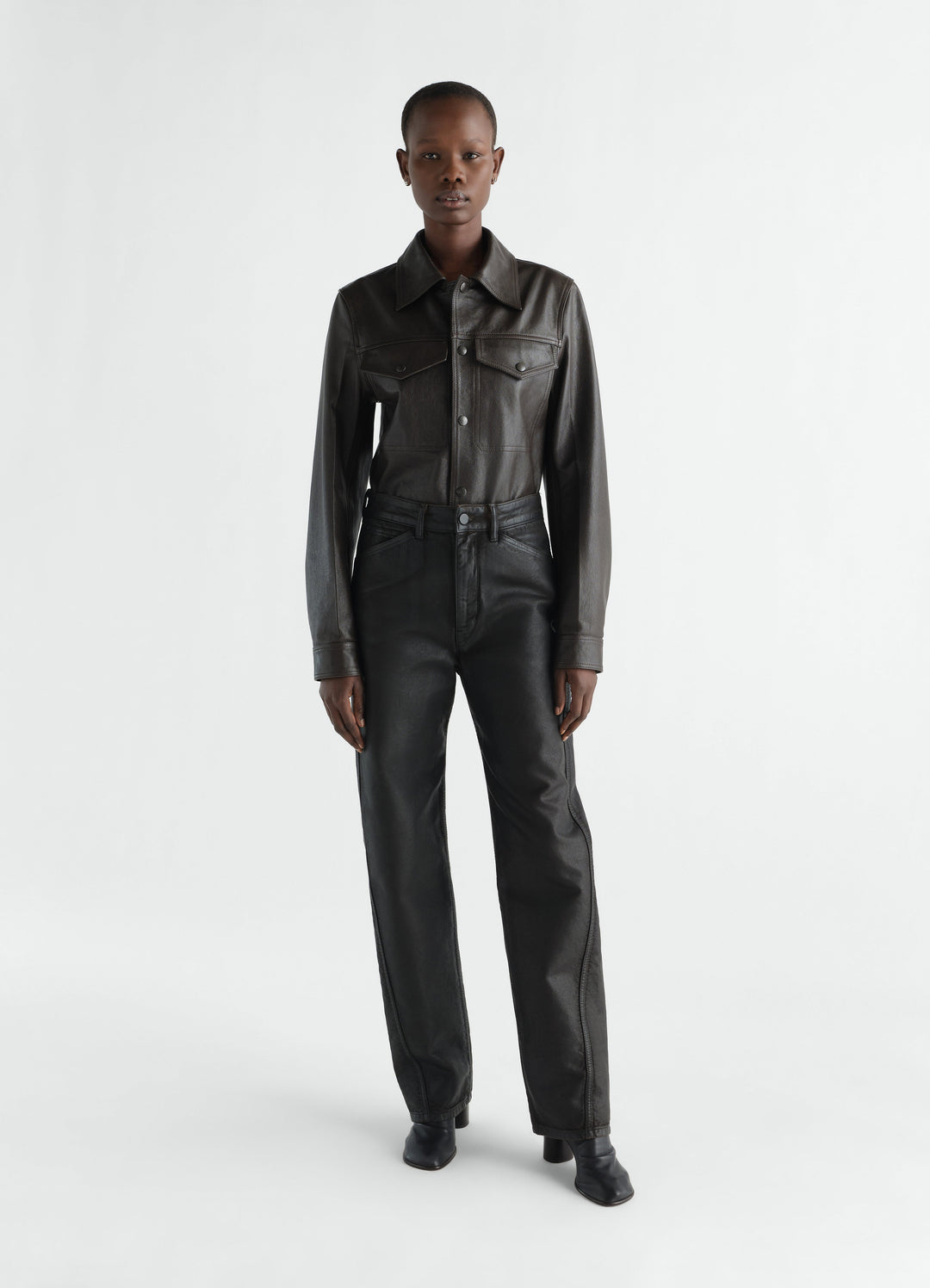 Twisted black coated denim pants worn by model front view LEMAIRE