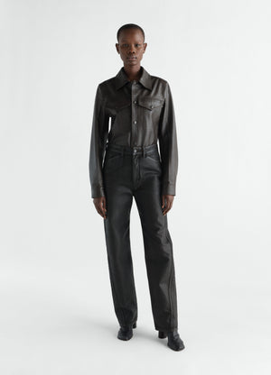 Twisted black coated denim pants worn by model front view lemaire