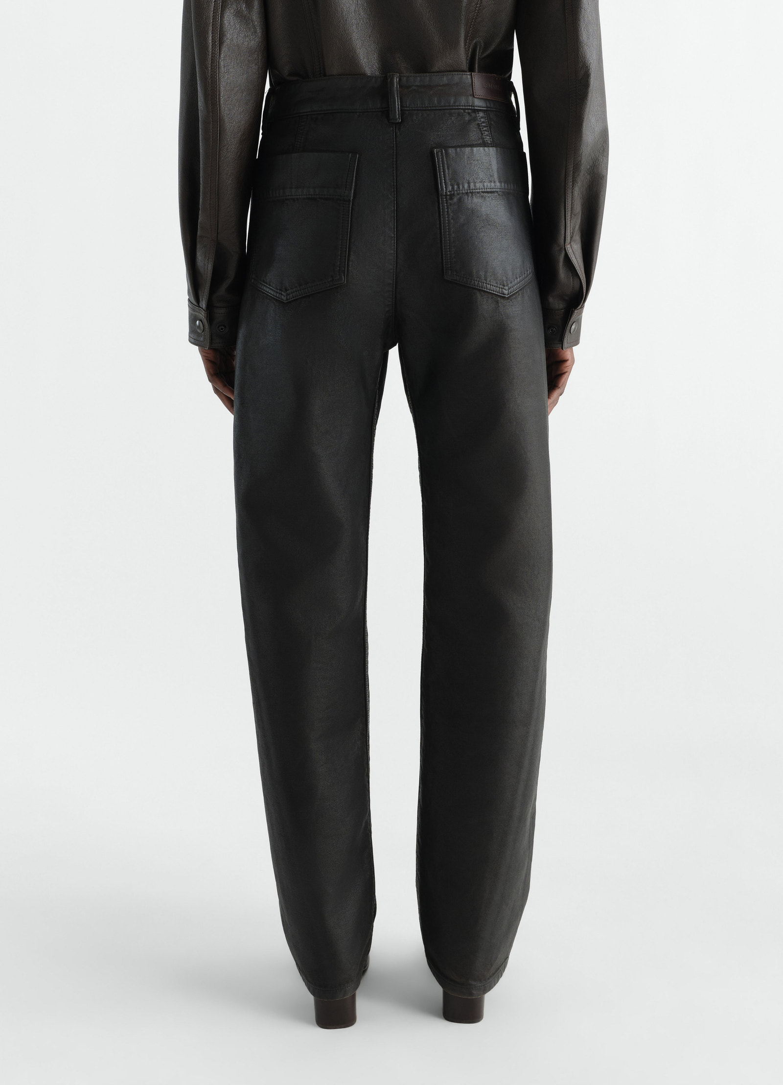 Twisted black coated denim five-pocket pants worn by model back view lemaire