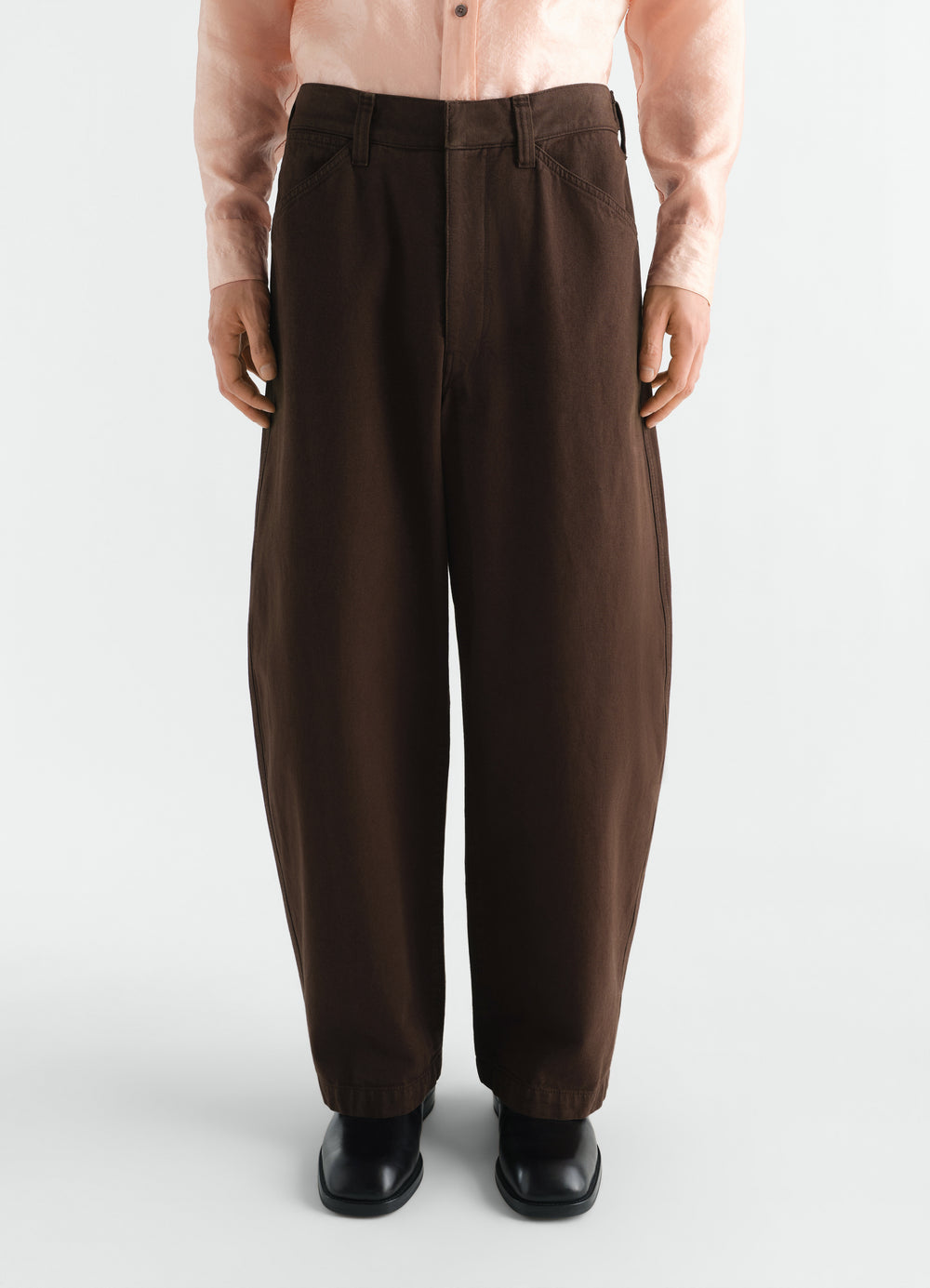 Oversized brown heavy garment-dyed twill pants by LEMAIRE worn by model front view with black shoes and pink shirt