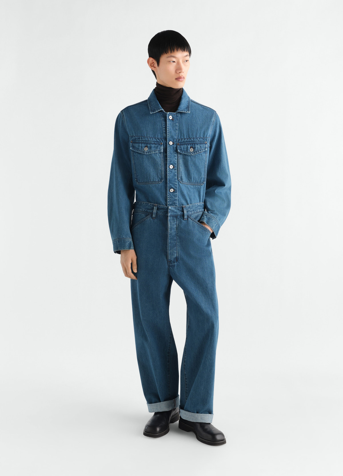 Oversized indigo selvedge denim workwear pants by lemaire worn by model with cuffed hems and black shoes