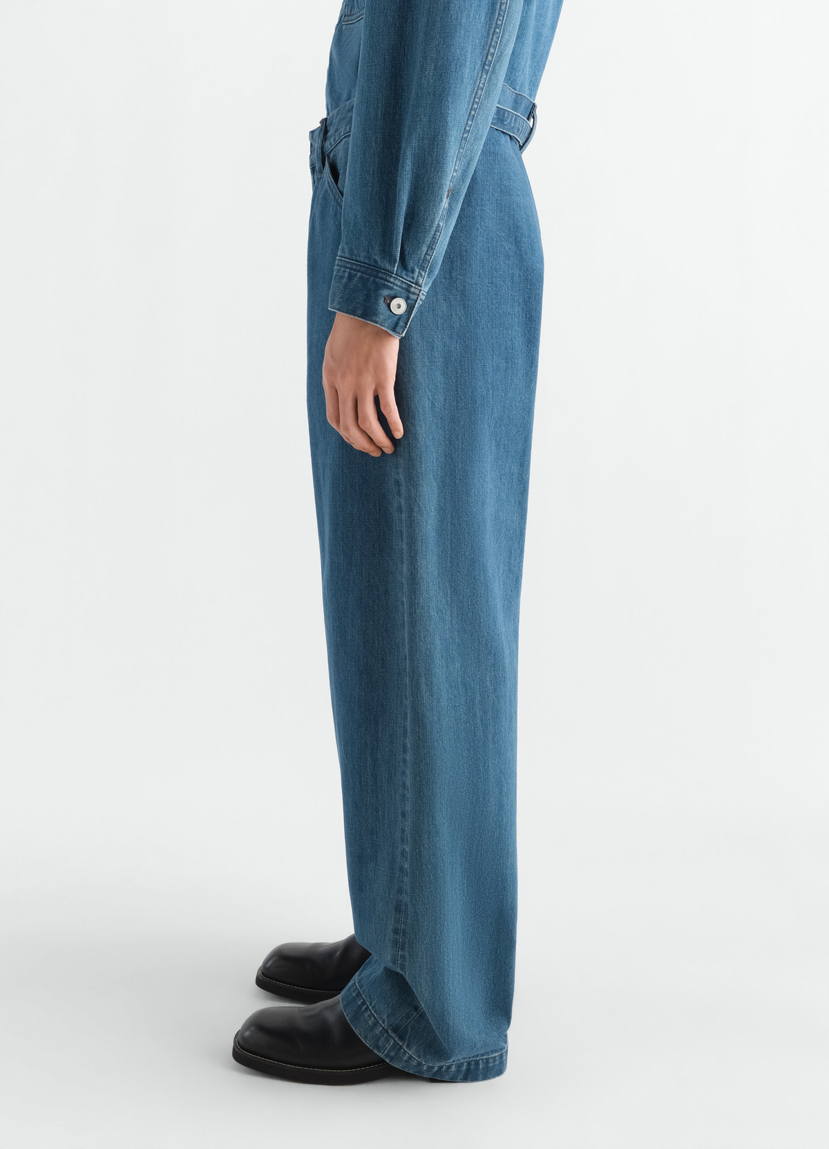 Oversized indigo selvedge denim workwear pants lemaire worn by model side view with black shoes