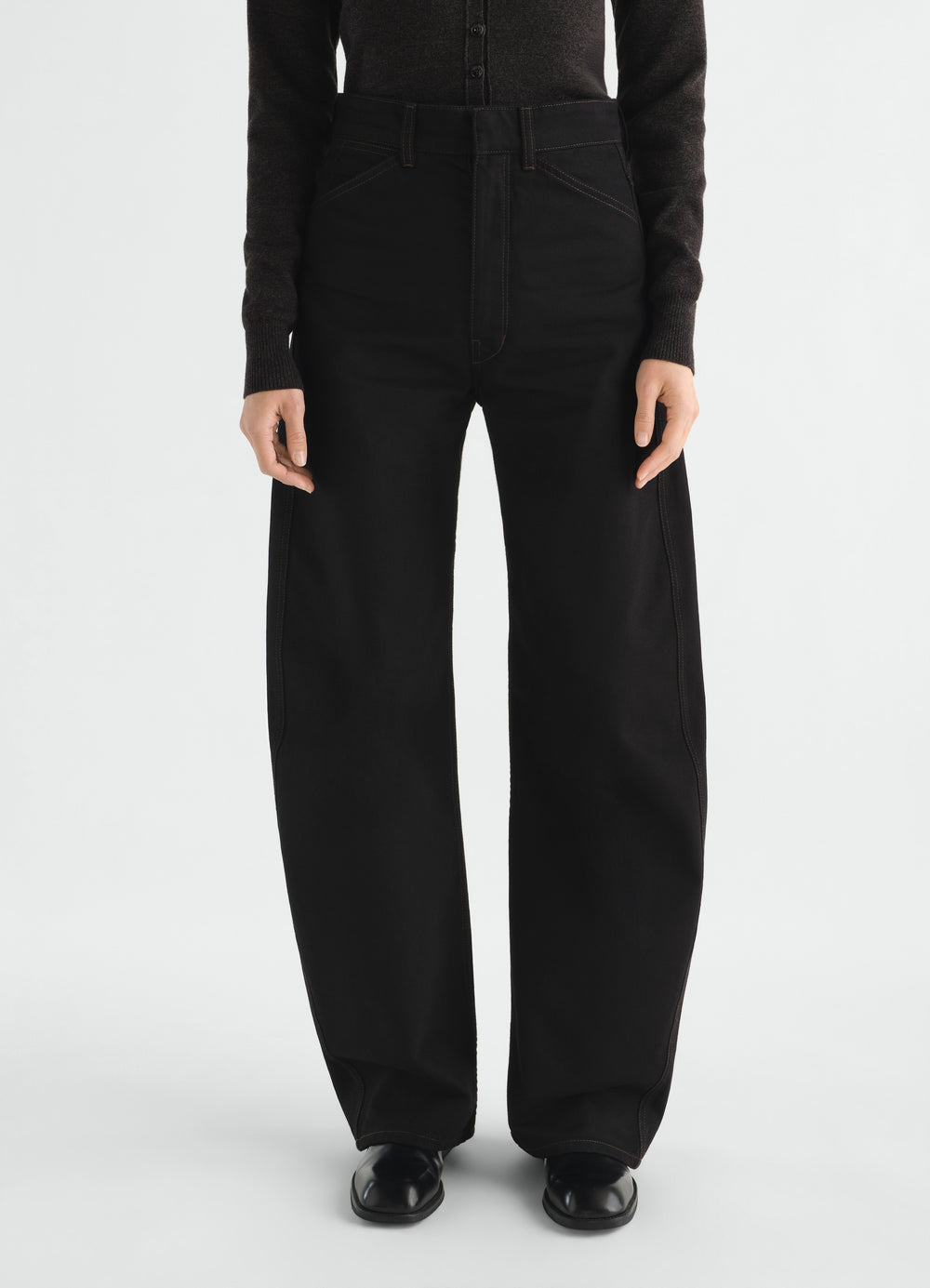 High waisted black denim pants with curved seams by LEMAIRE worn by a model front view