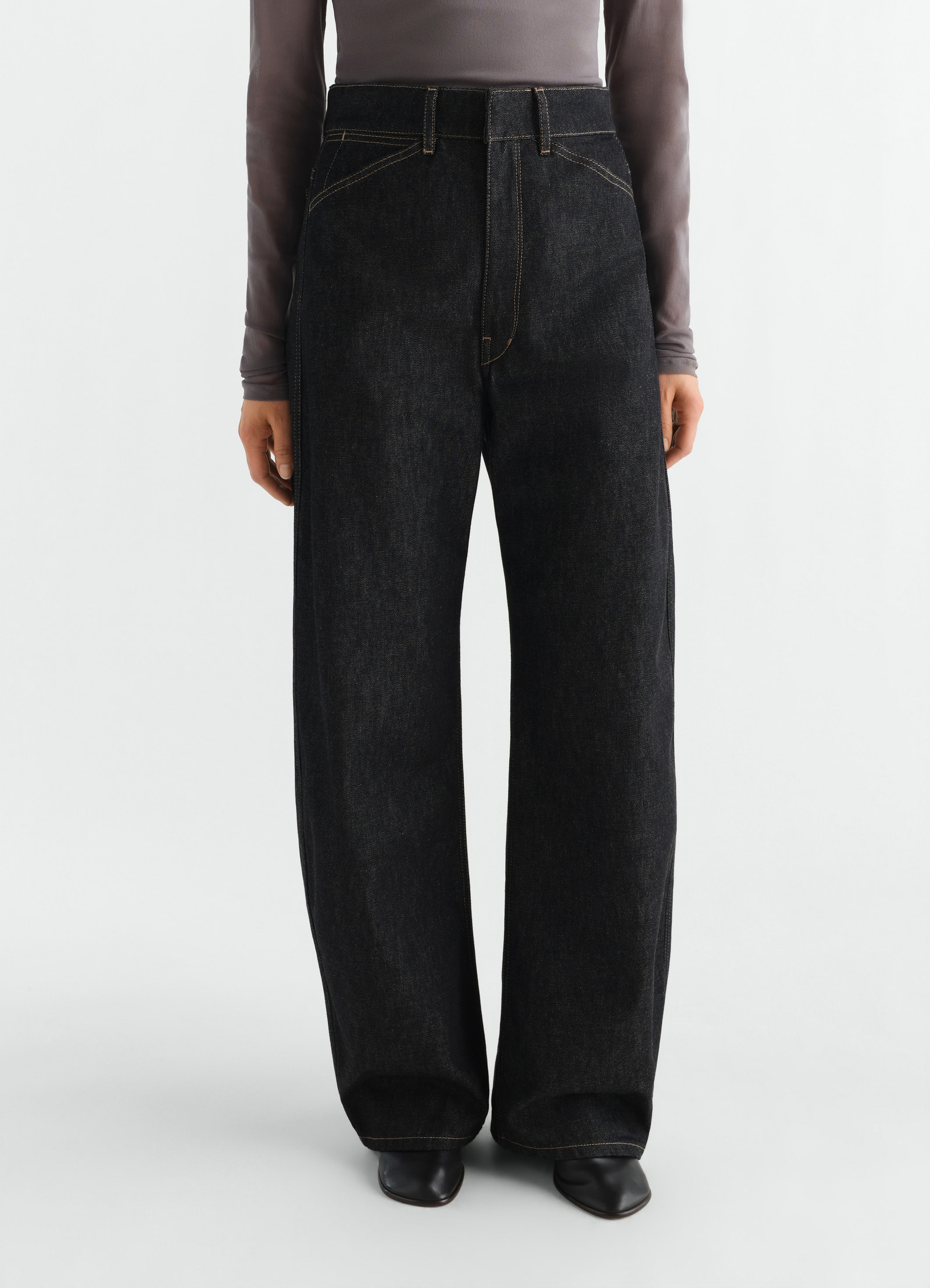 High waisted black denim curved pants with yellow stitching worn by a model lemaire front view