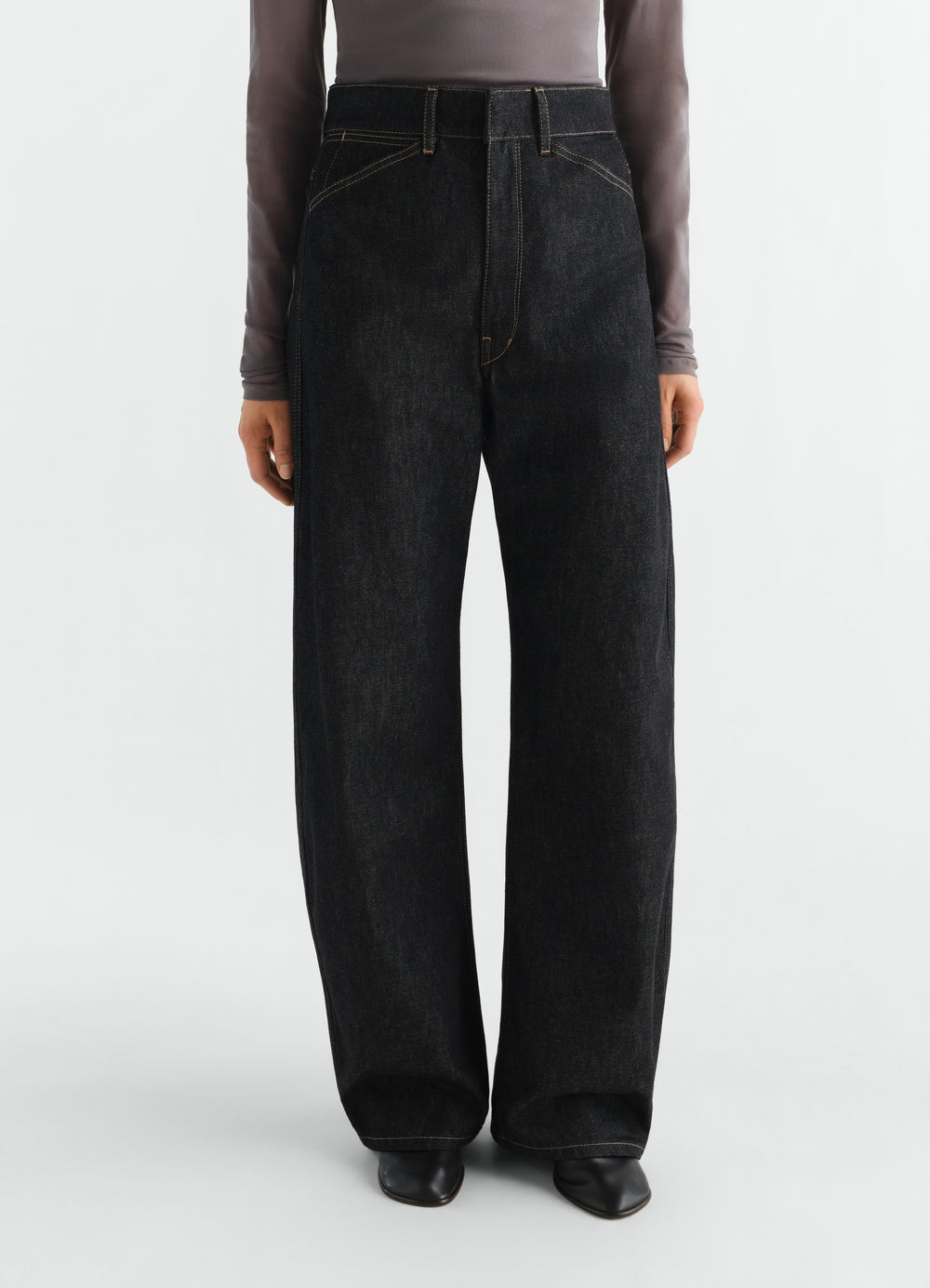 High waisted black denim curved pants with yellow stitching worn by a model LEMAIRE front view
