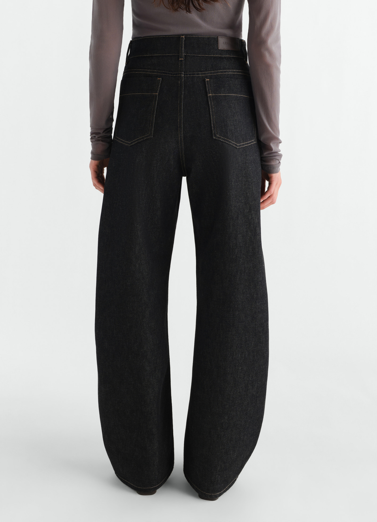 High waisted black denim curved pants with back pockets by lemaire worn by model back view