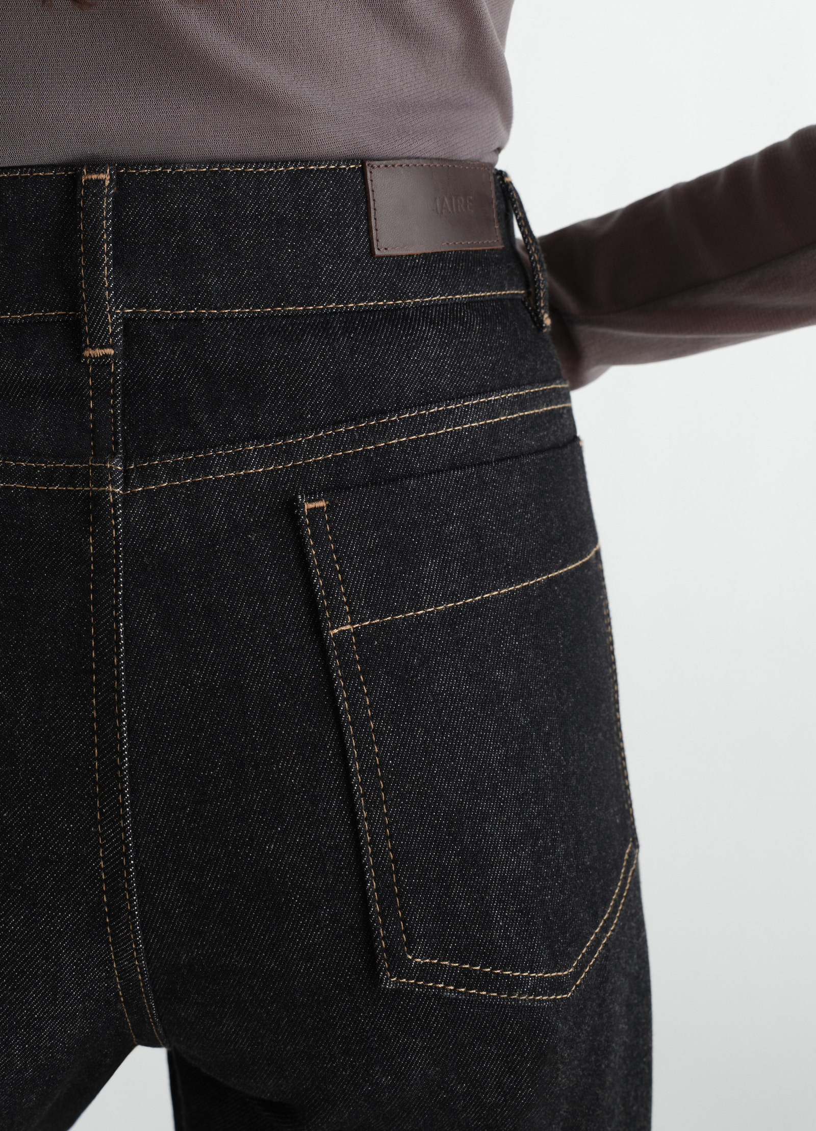 High waisted black denim pants with contrast stitching by lemaire worn by a model, back close-up detail