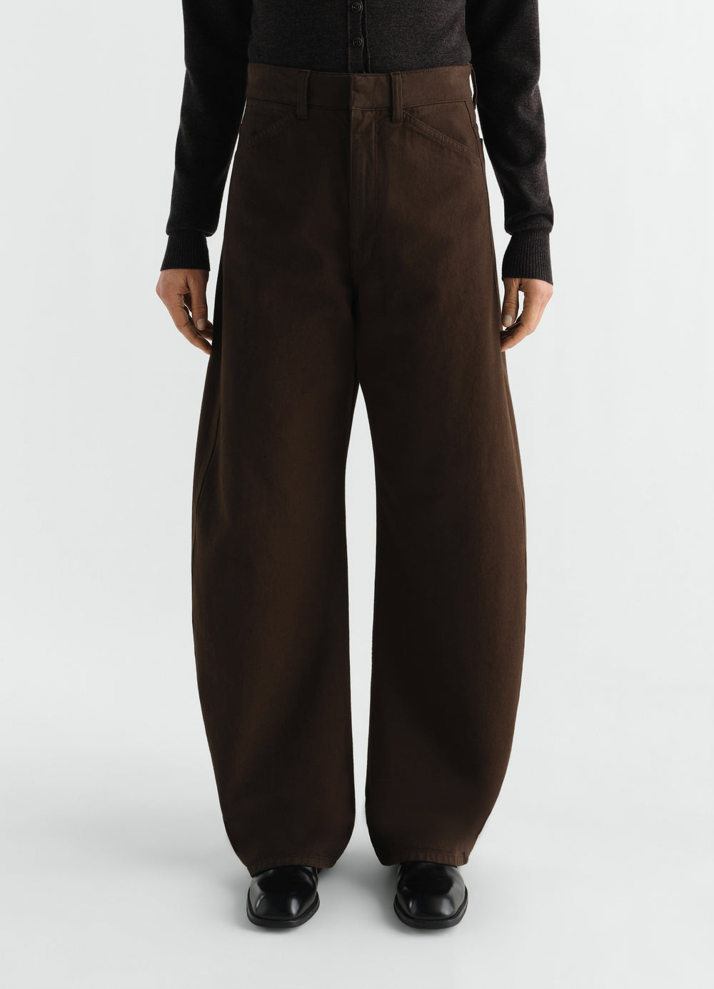 High waisted curved brown twill pants by LEMAIRE worn by model front view with black top and shoes