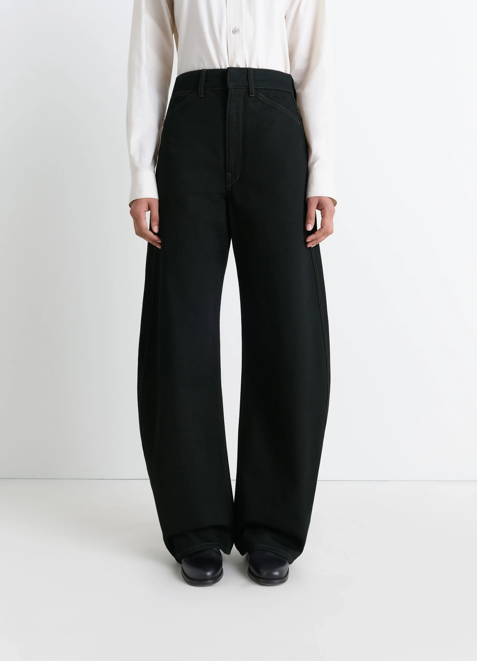 Lemaire high waisted curved pants in deep black thick denim, model shot, front three-quarter view wide leg draped silhouette