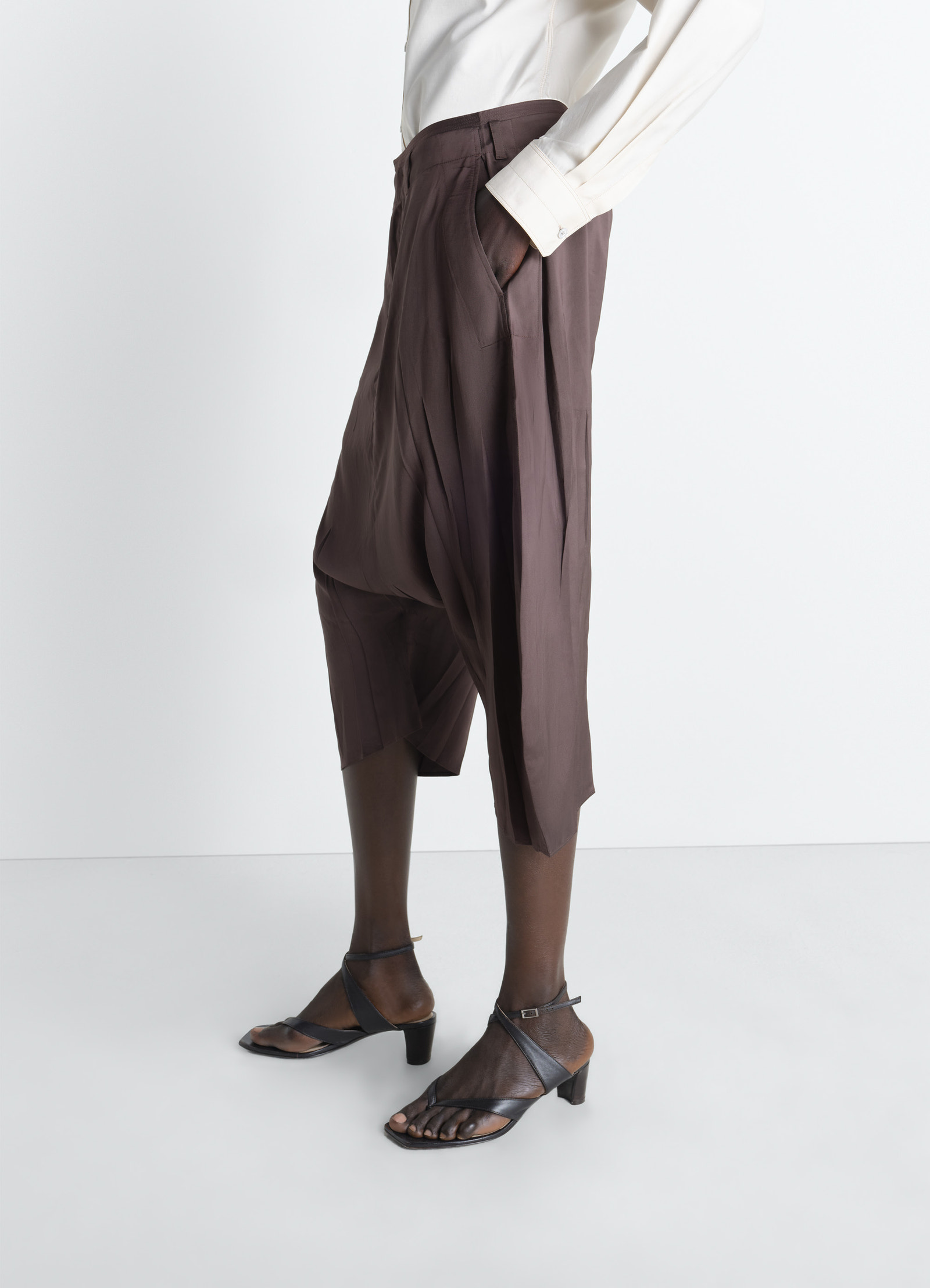 Creased dropped crotch bermudas in poly viscose twill, model shot, three-quarter perspective creased pocket detail