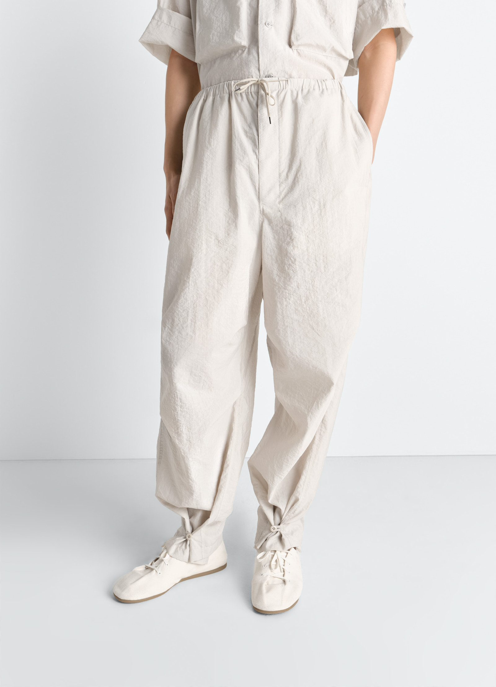 Lemaire parachute pants in washed technical cotton, model shot, angled front view adjustable waist drawstring