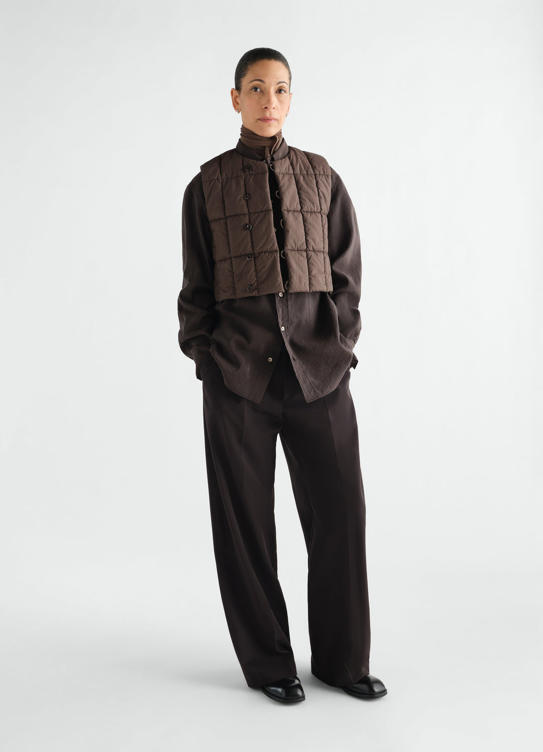 Wide pleated wool gabardine pants in dark brown worn by model LEMAIRE front view styled look