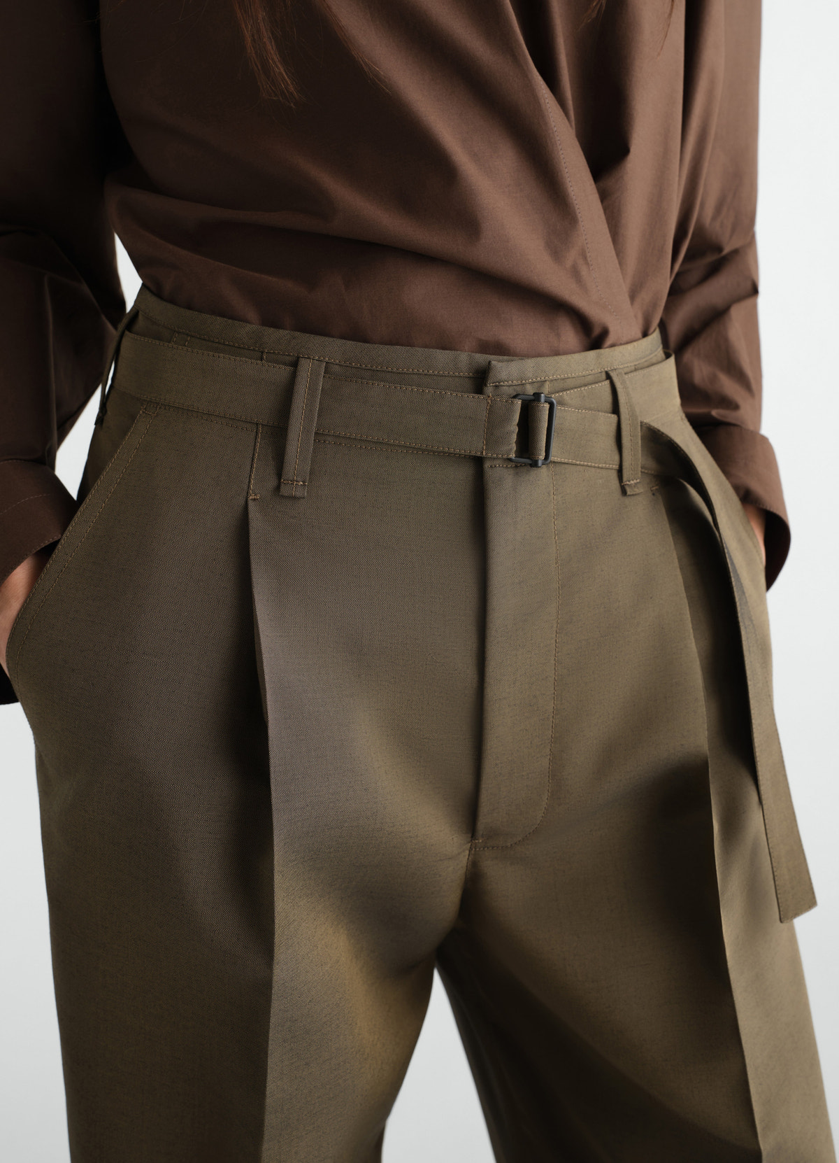 Wide pleated wool mohair pants in olive green with belt detail worn by model lemaire