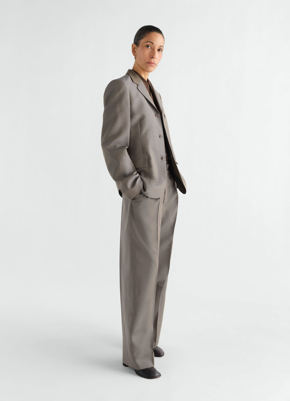 WEITE FALTENHOSE AUS WOLL- UND MOHAIR-STOFF, in Taupe, von einem Model getragen, Seitenansicht, Falten sichtbar