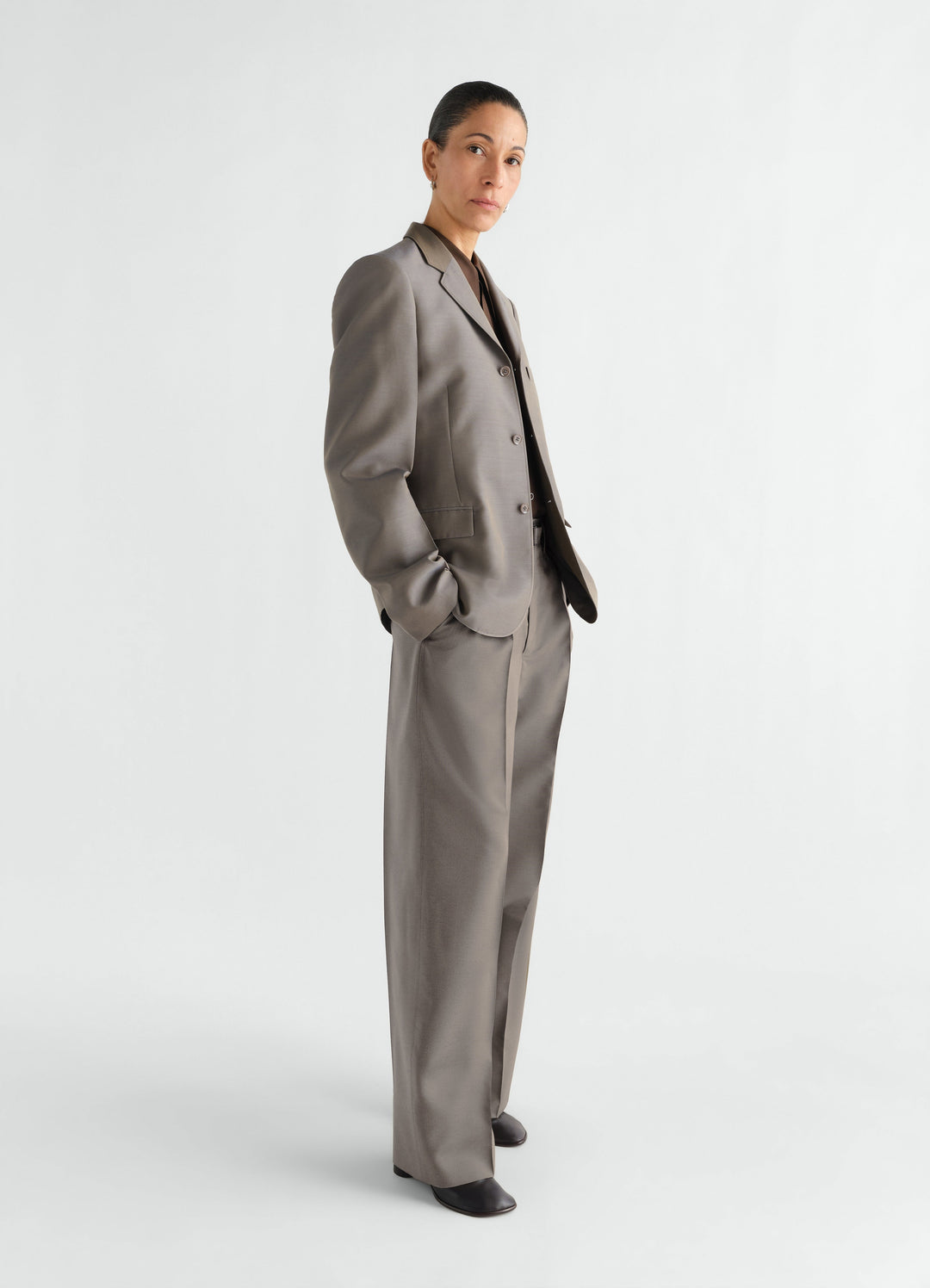 Wide pleated wool and mohair pants in taupe worn by model side view LEMAIRE