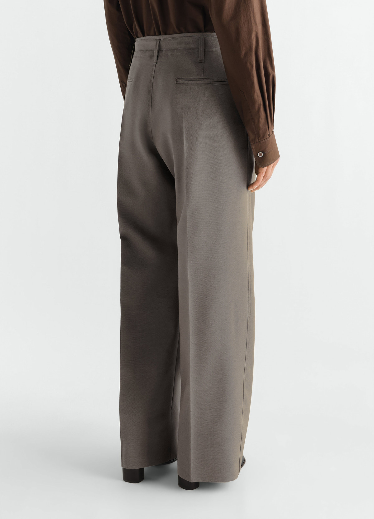 Wide pleated grey wool mohair pants lemaire worn by model back view with brown shirt and black shoes