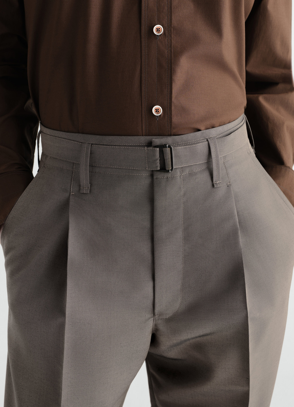 Wide pleated grey wool mohair pants with belt worn by model lemaire close-up front detail