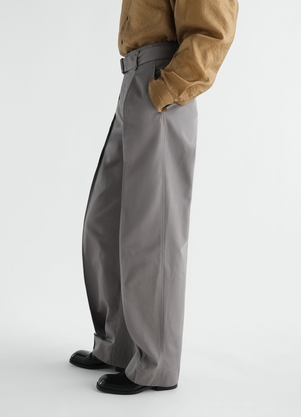 Hose mit abgerundetem schnitt aus poly-baumwoll-twill, in grau, von einem model getragen, seitenansicht