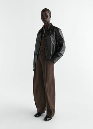 Rounded brown polycotton twill pants by lemaire worn by a model with black leather jacket on white background