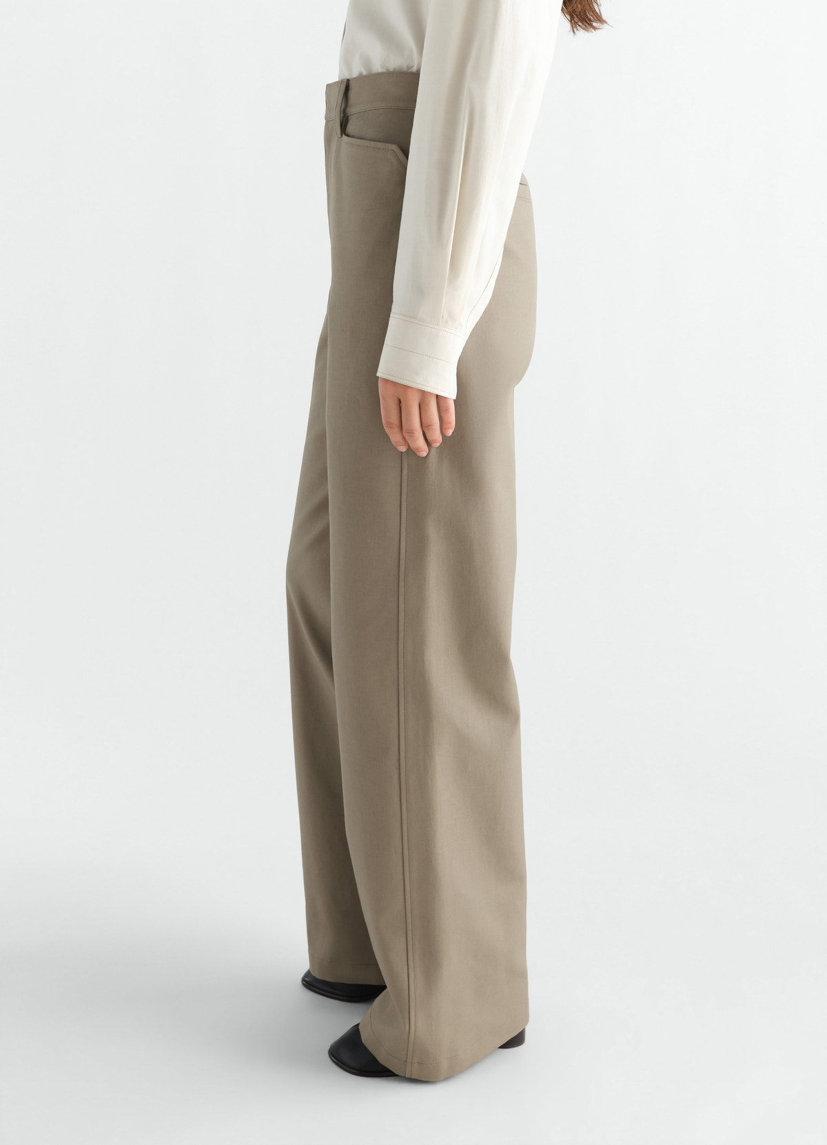 Straight beige heavy cotton twill pants lemaire worn by a model side view with long sleeve blouse and boots