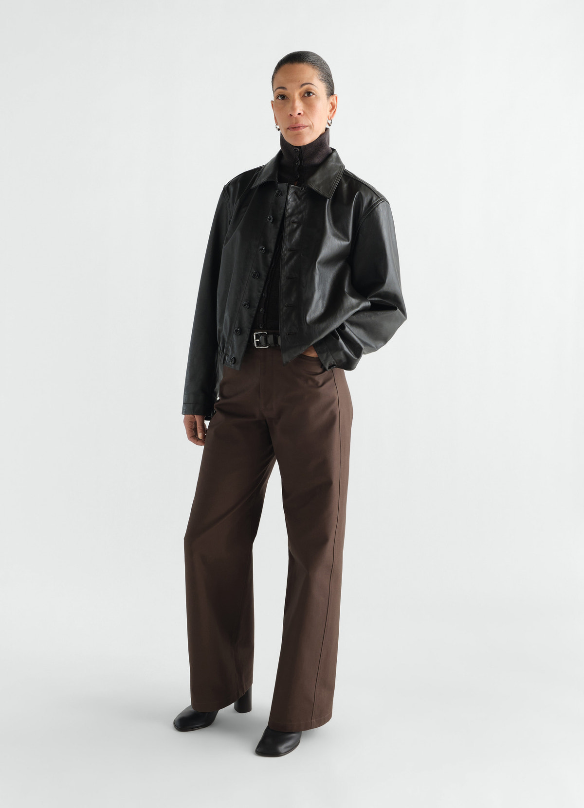 Straight brown heavy cotton twill pants lemaire worn by model with black leather jacket front view