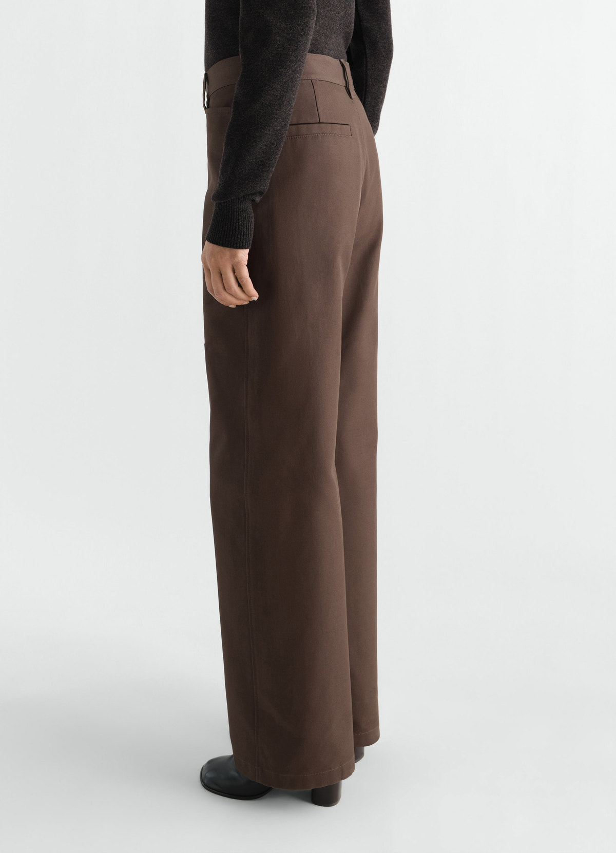 Straight brown heavy cotton twill pants by lemaire worn by model side view with black boots and sweater