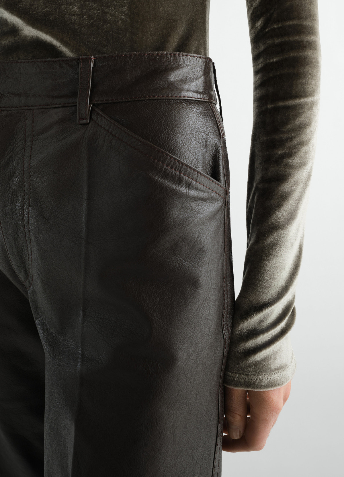 Bermuda en cuir glossy, coloris marron foncé, porté par un mannequin, gros plan de face, manches visibles
