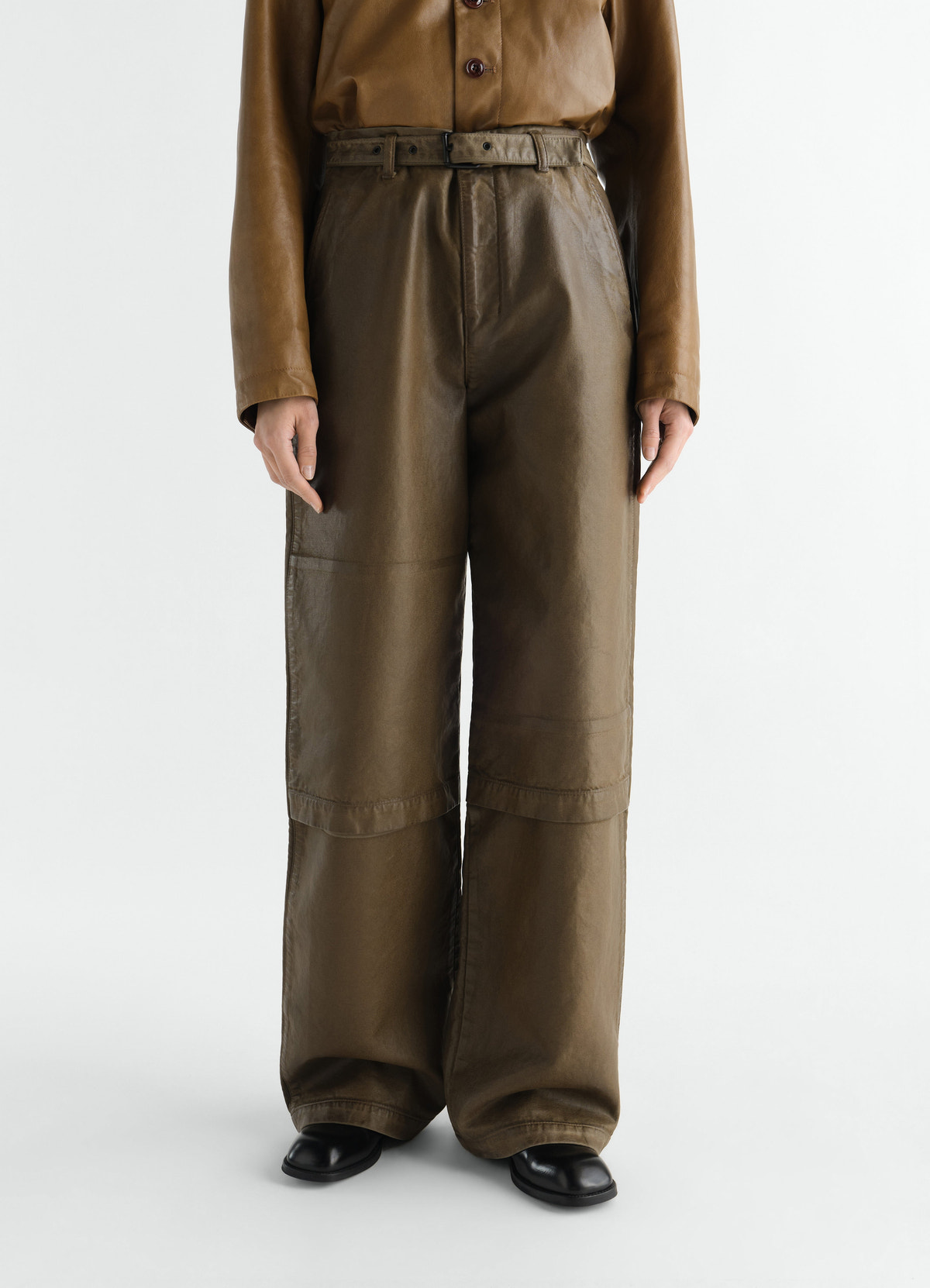 Work pants in coated olive broken twill with belt worn by model front lemaire
