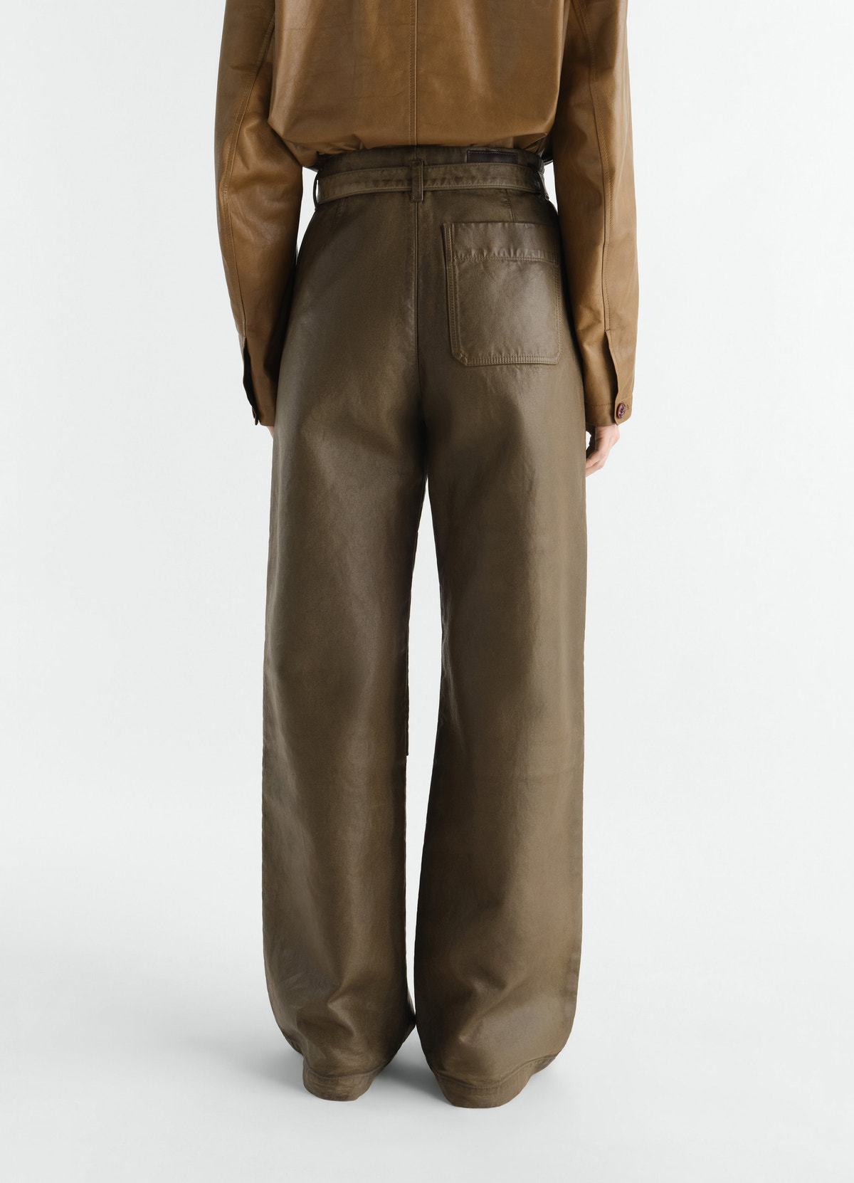Work pants in olive coated broken twill worn by a model showing rear view lemaire