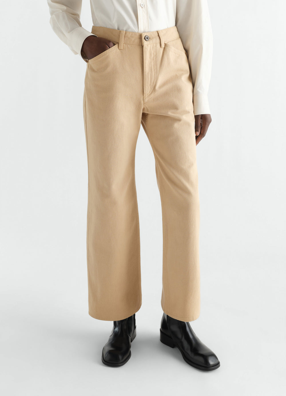 Flared beige cotton twill pants LEMAIRE worn by model front view with black boots and white shirt